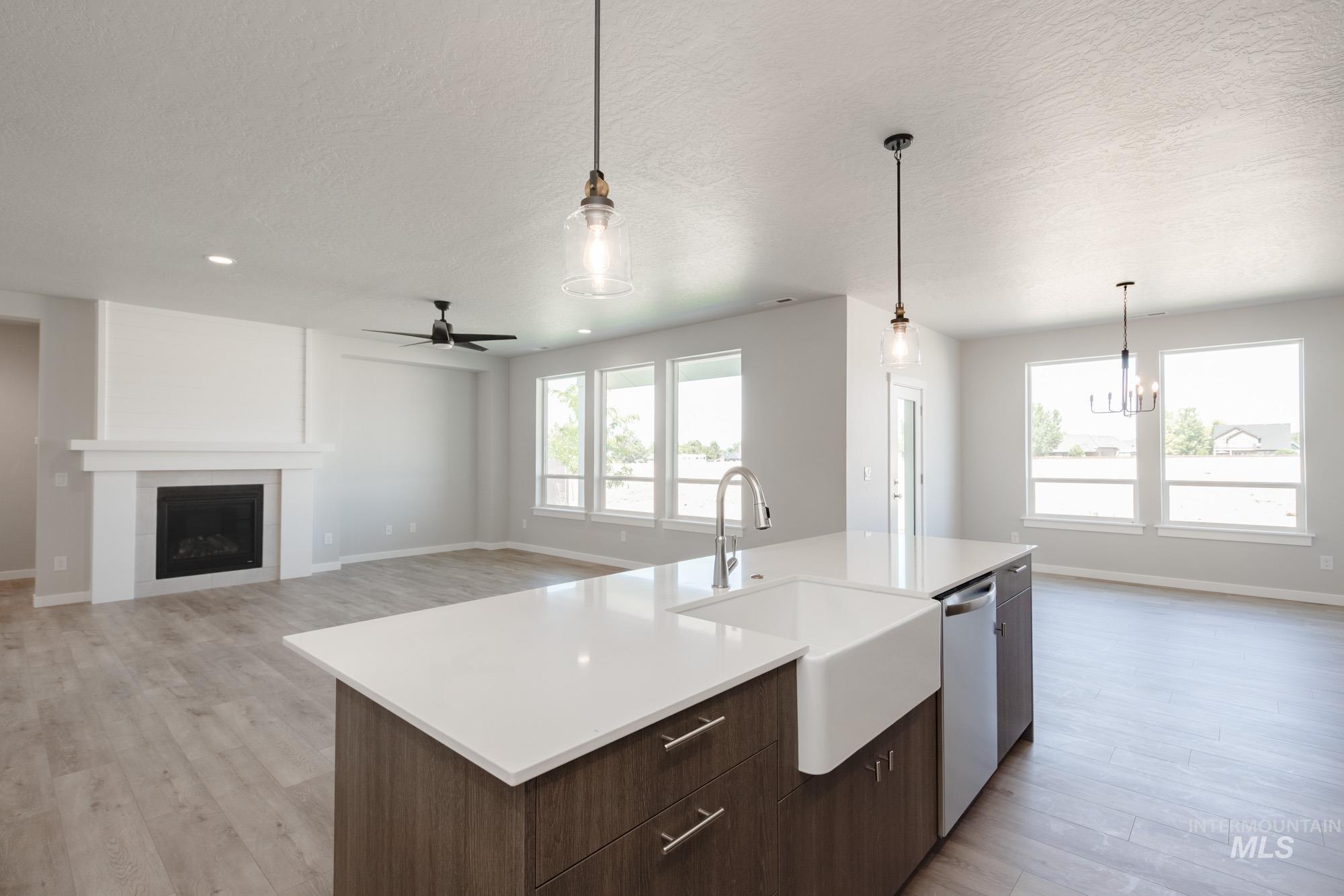 Kitchen featuring light wood-style flooring, a fireplace, light countertops, ceiling fan, and dark brown cabinets