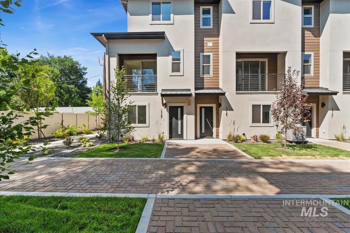 View of front facade featuring a balcony, stucco siding, and a metal roof