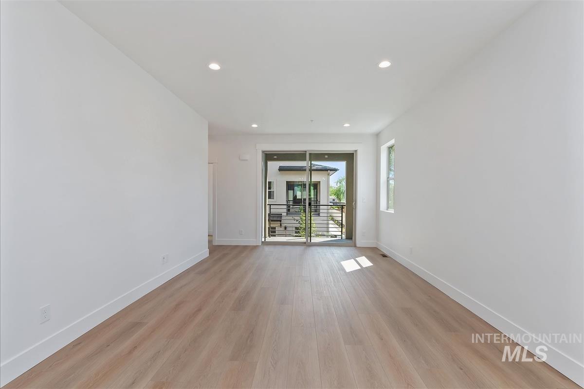Empty room with light wood-style floors and recessed lighting