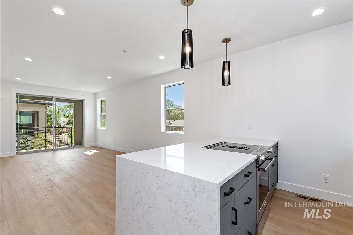 Kitchen with recessed lighting, stainless steel electric stove, light wood-style floors, pendant lighting, and a peninsula