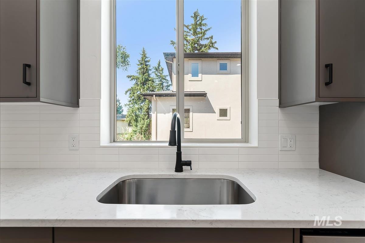 Kitchen featuring healthy amount of natural light, light stone countertops, and tasteful backsplash