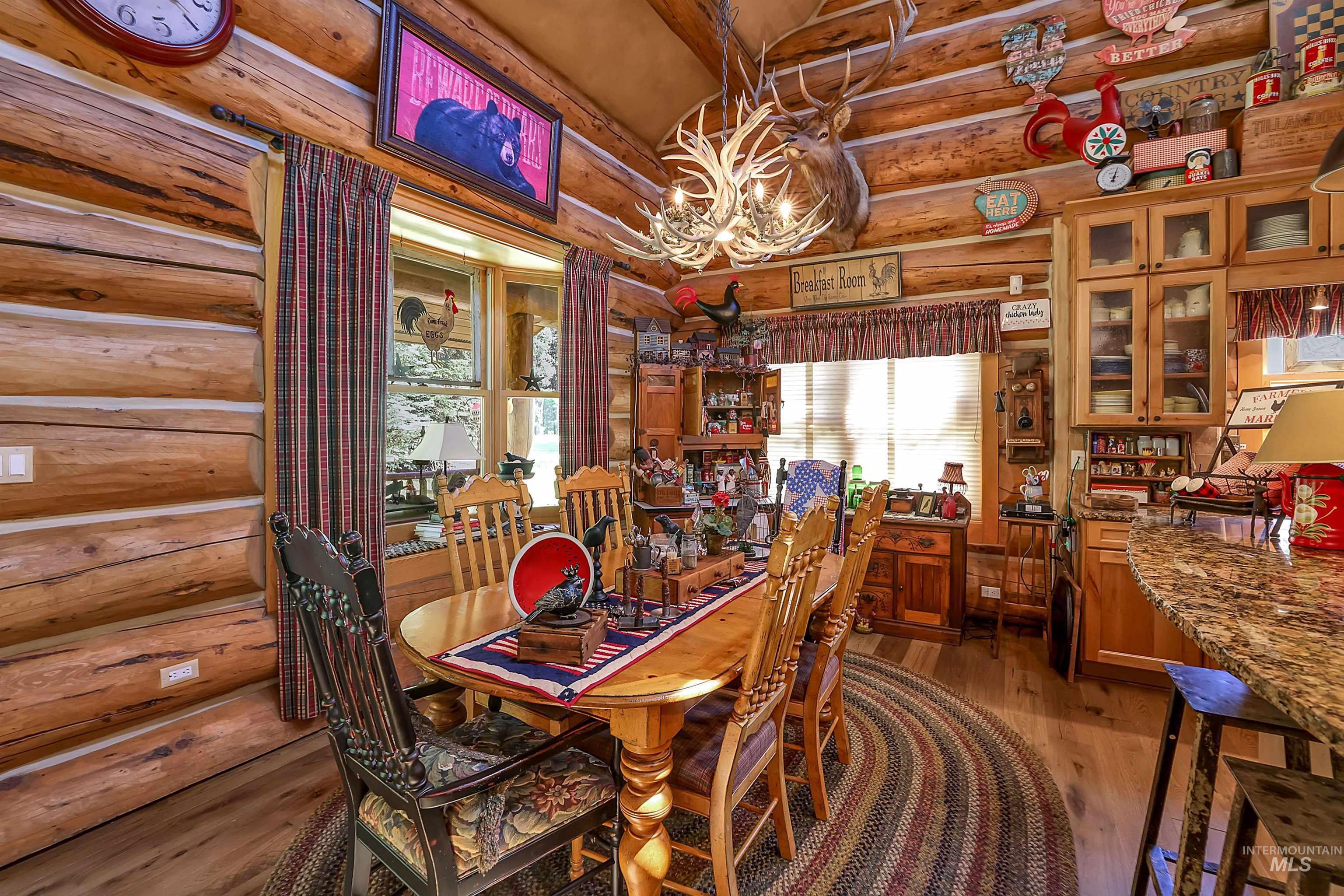 Dining space featuring rustic walls, a chandelier, light wood finished floors, plenty of natural light, and lofted ceiling