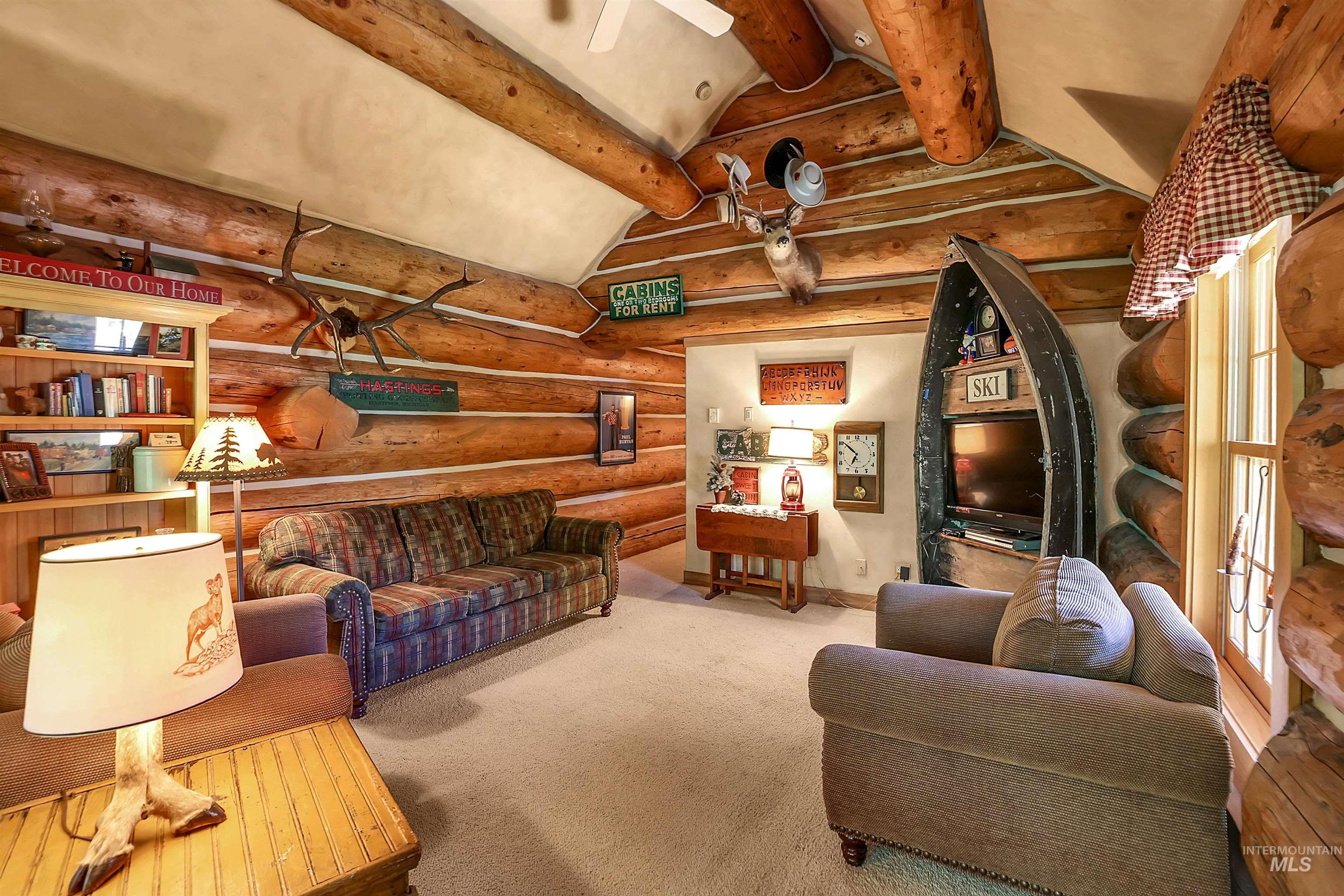 Living area featuring rustic walls, carpet floors, and ceiling fan