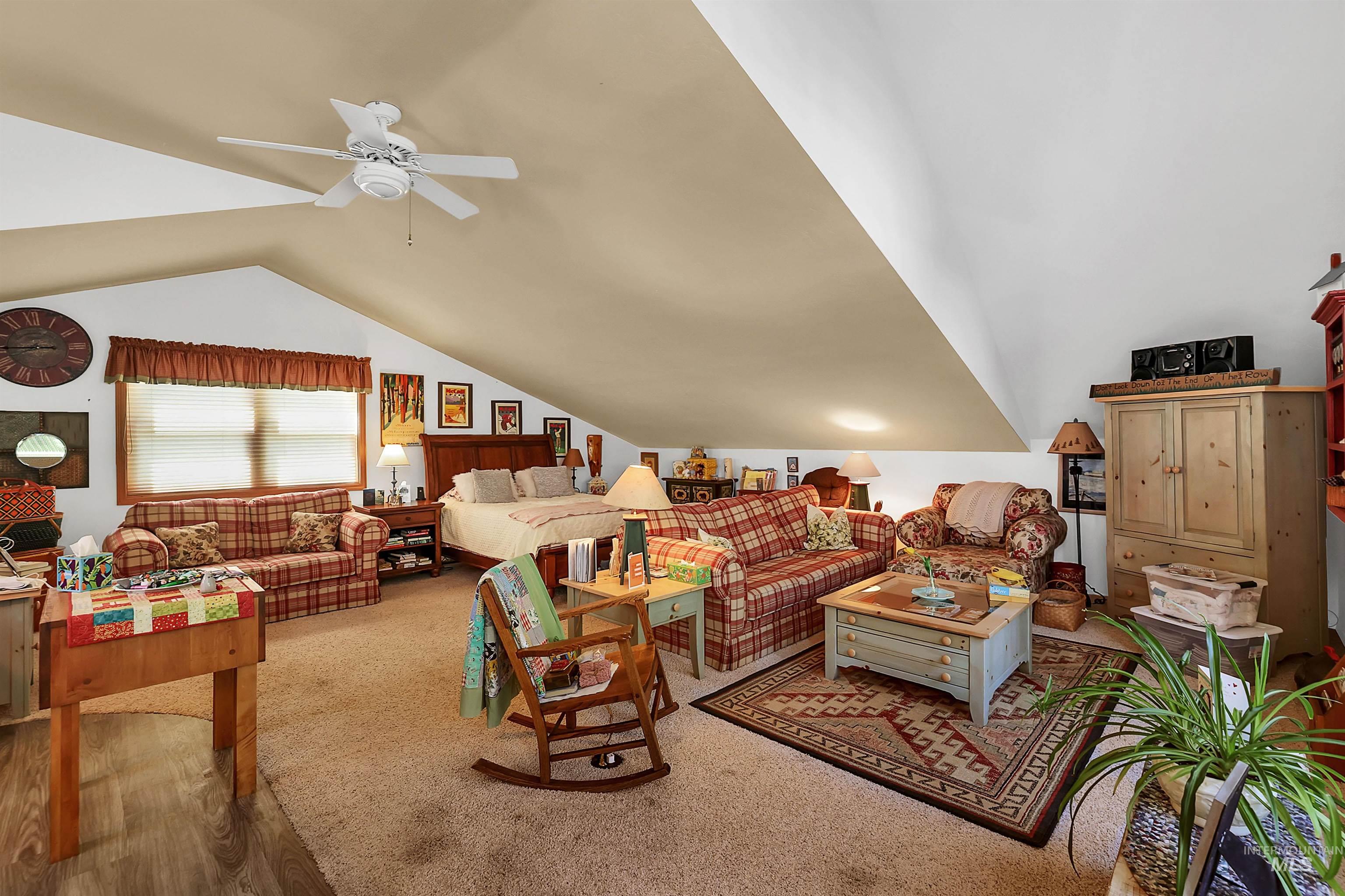 Living room featuring vaulted ceiling, ceiling fan, and carpet
