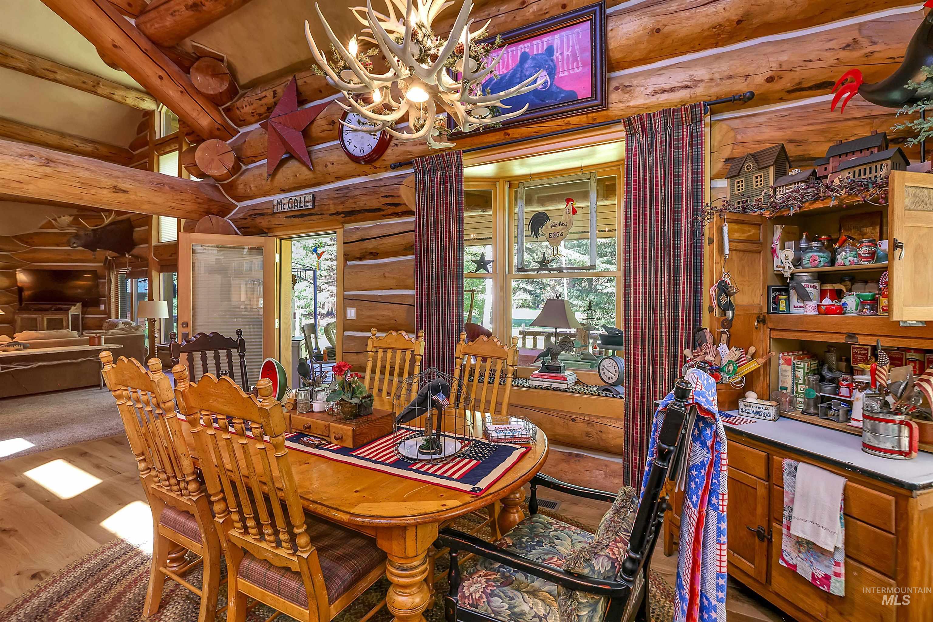 Dining room featuring log walls, a chandelier, and wood finished floors