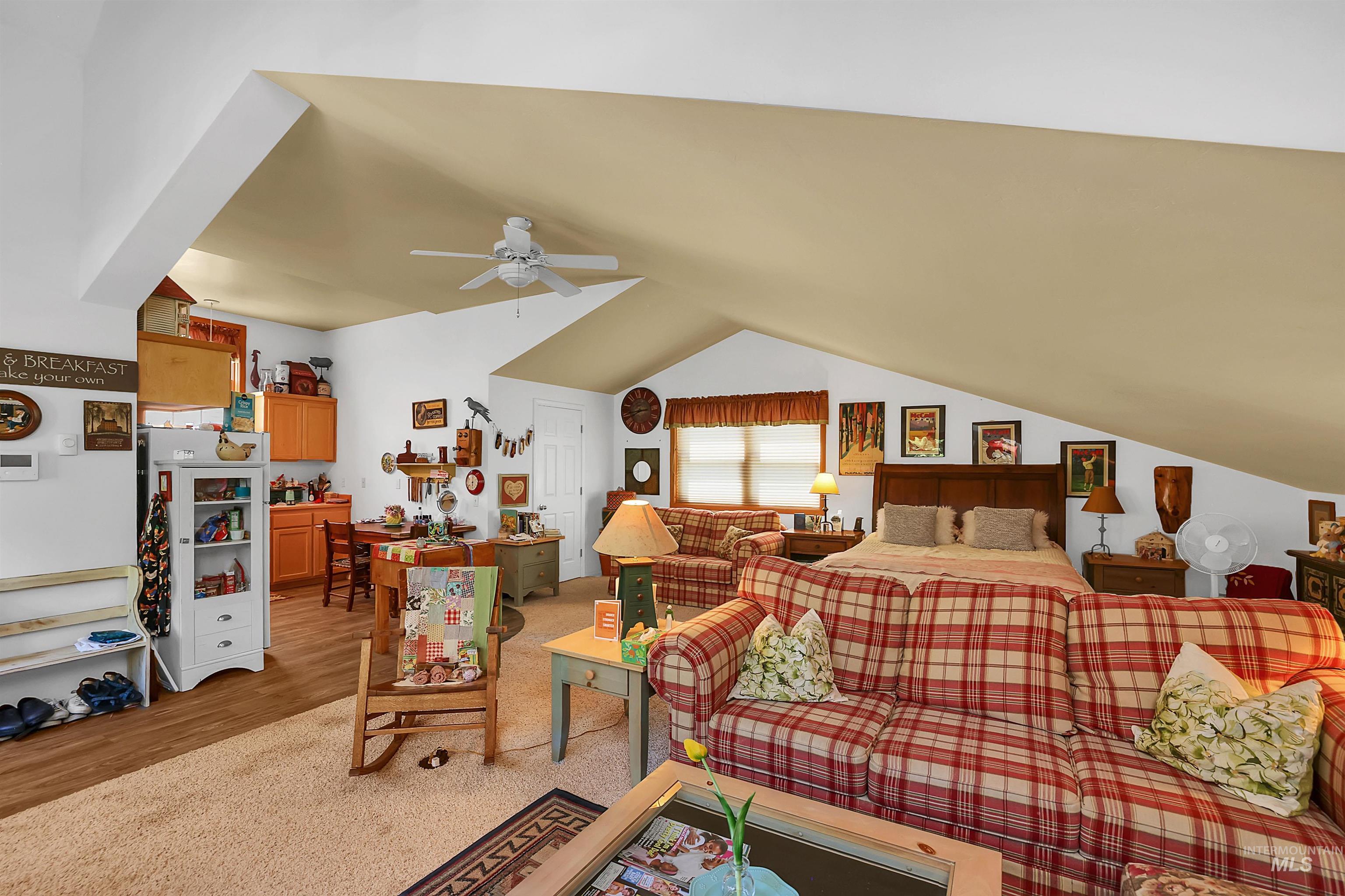 Bedroom with light wood finished floors, vaulted ceiling, and a ceiling fan