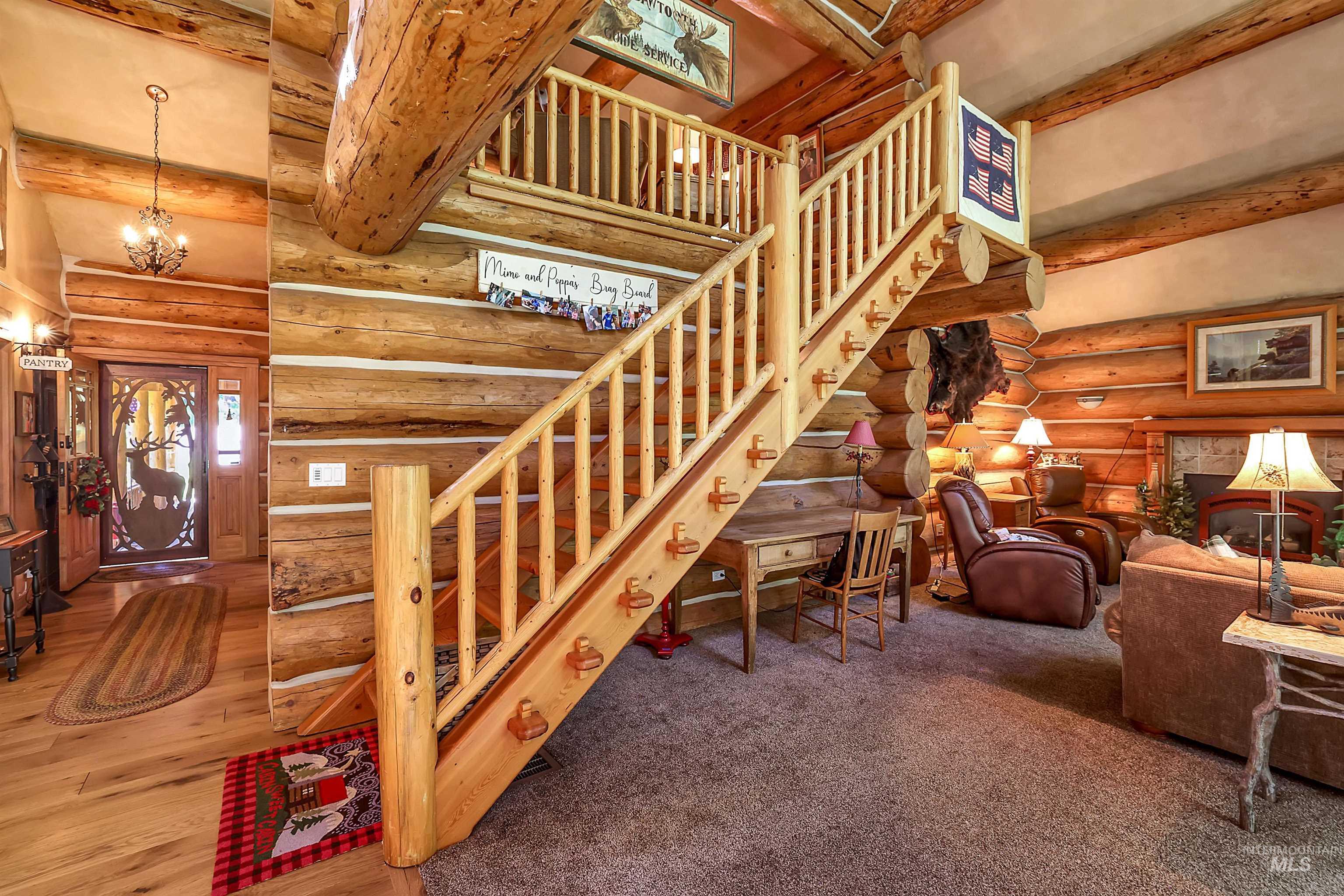 Living area with beam ceiling, stairway, rustic walls, a chandelier, and wood finished floors