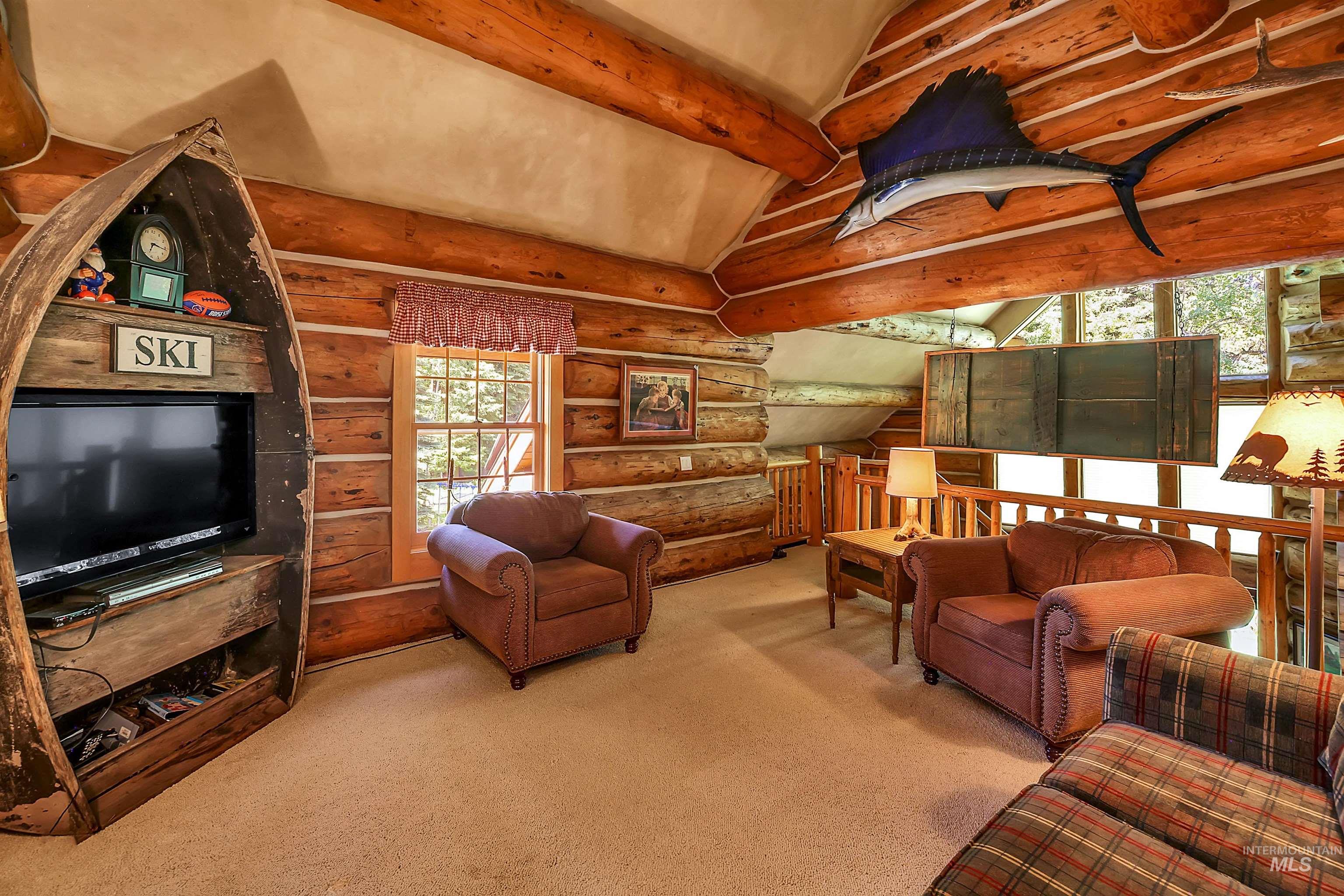 Carpeted living room featuring log walls