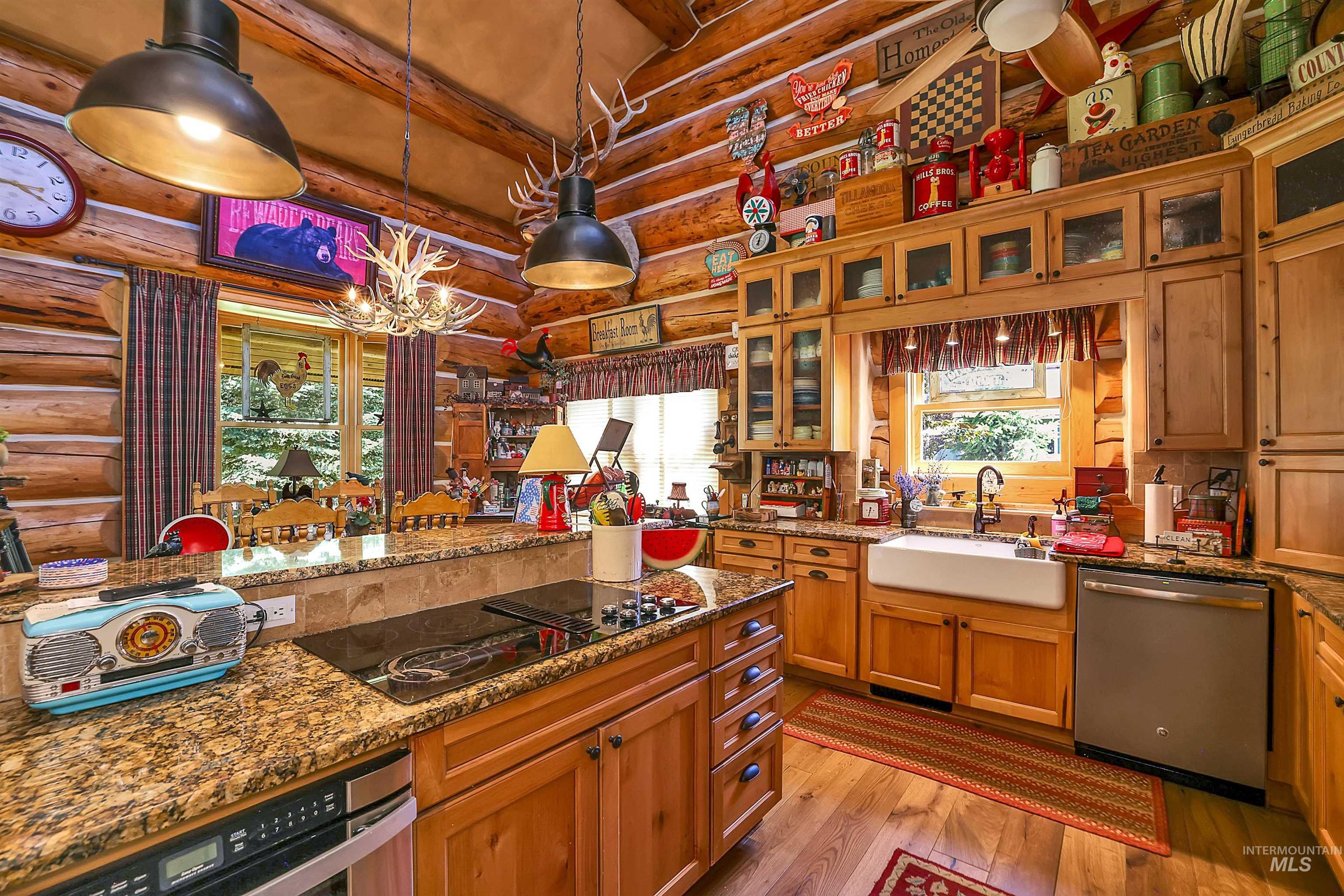 Kitchen with stainless steel appliances, rustic walls, light wood-style floors, a chandelier, and hanging light fixtures