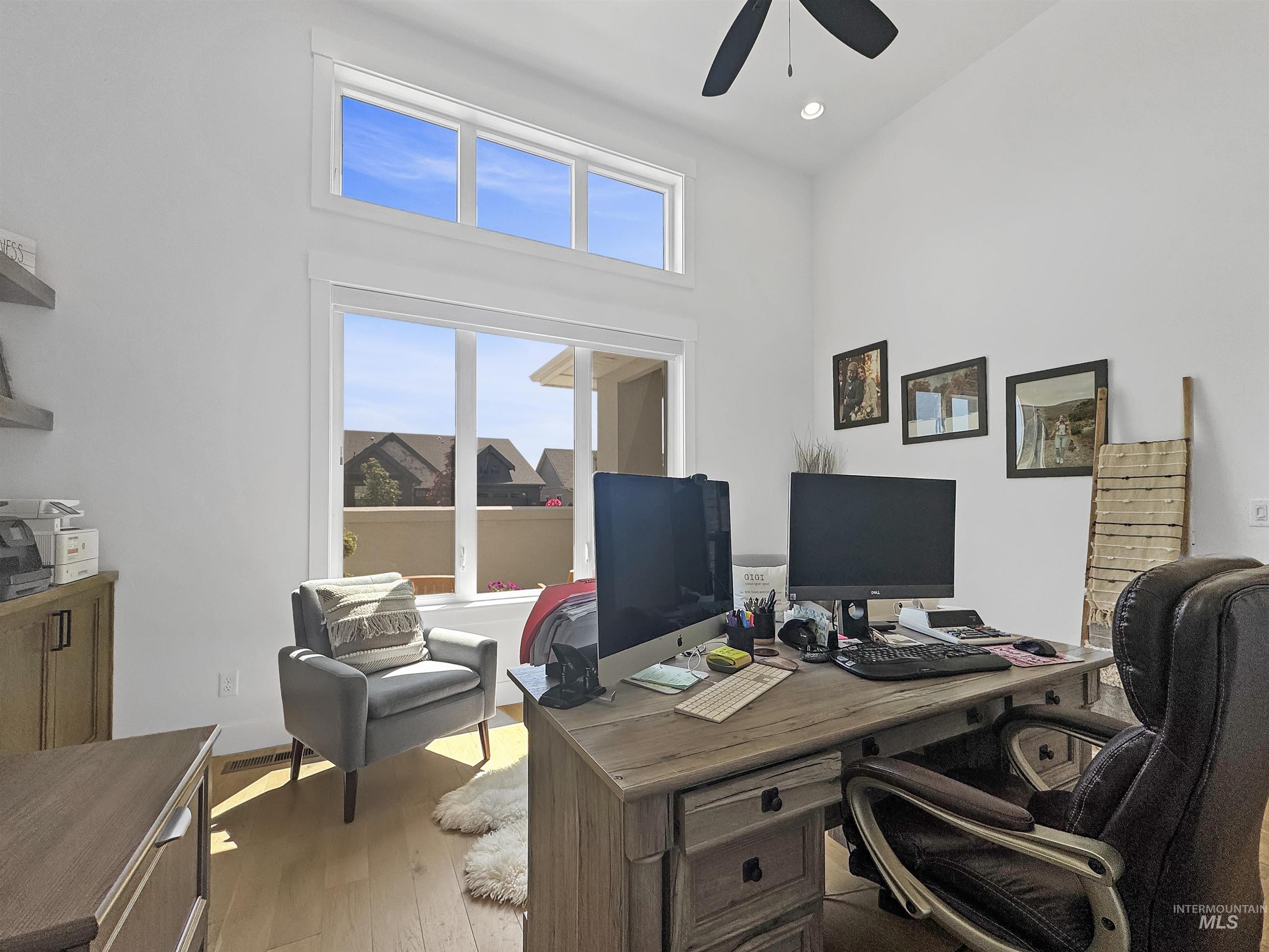 Office with light wood-style floors, a towering ceiling, ceiling fan, and recessed lighting
