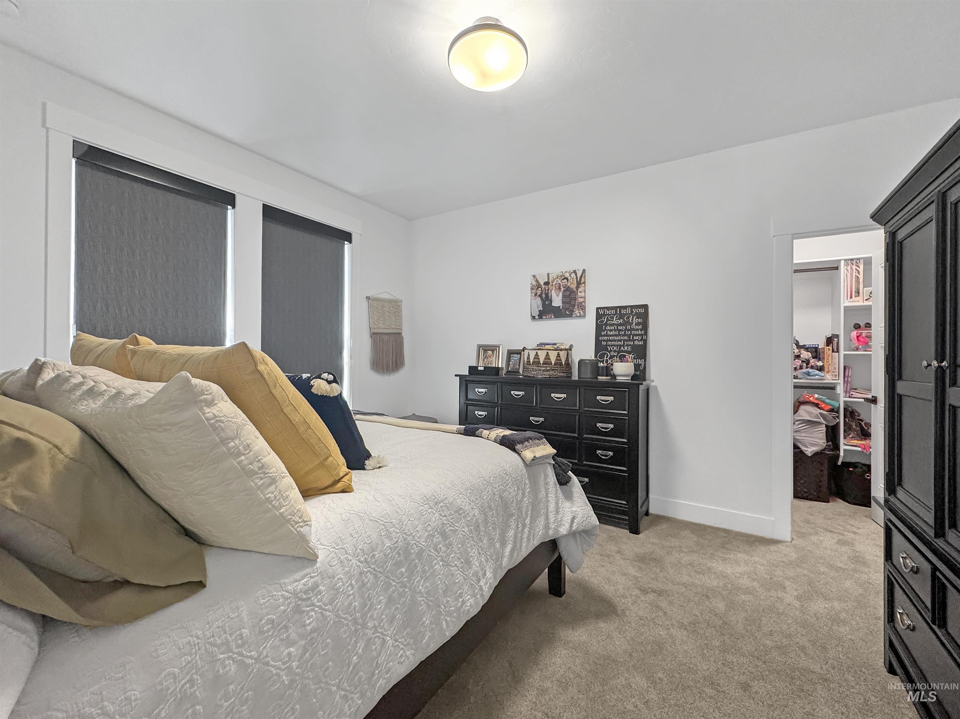 Bedroom with light colored carpet and a spacious closet