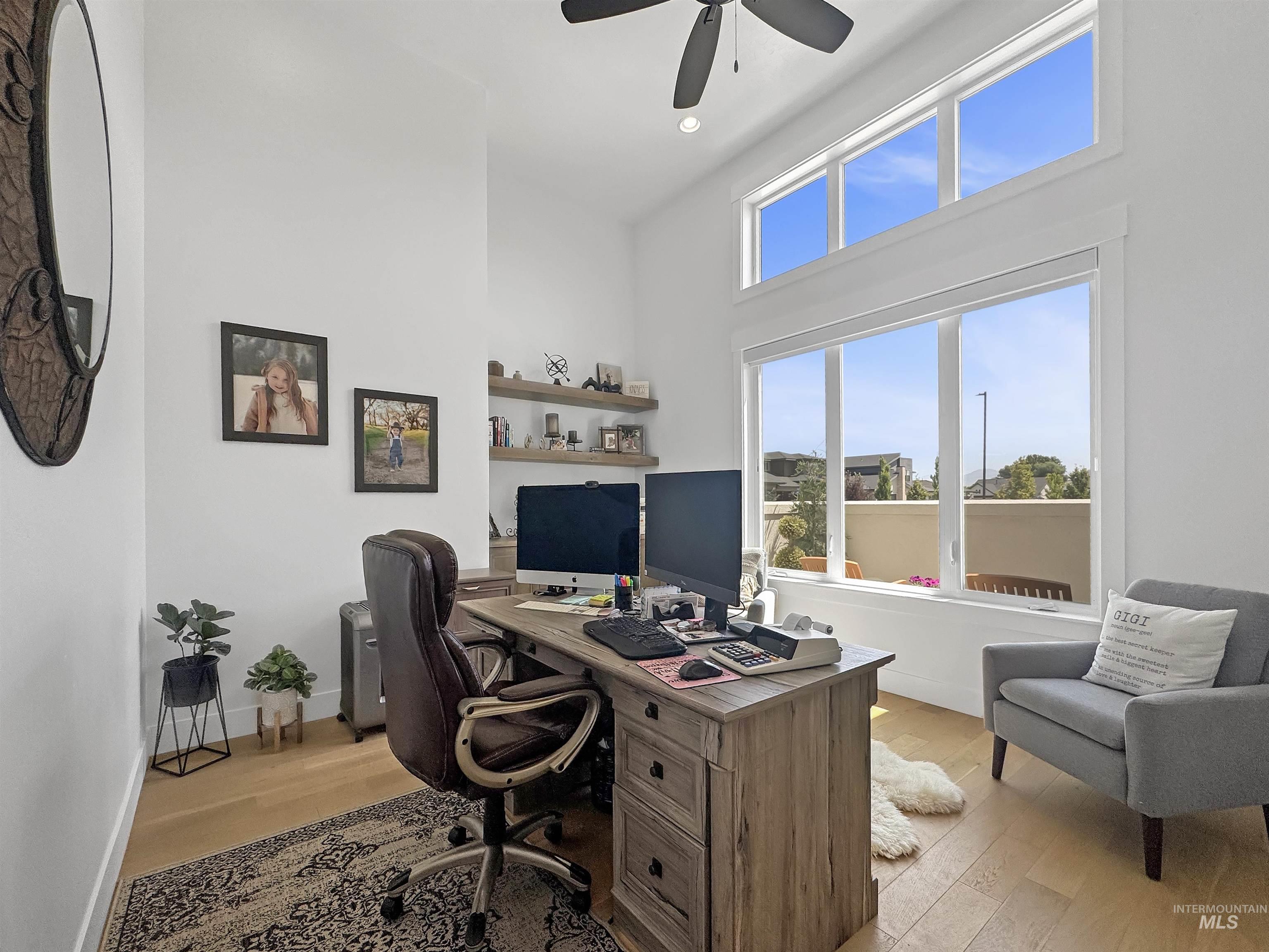 Office area with light wood finished floors, a ceiling fan, and a high ceiling