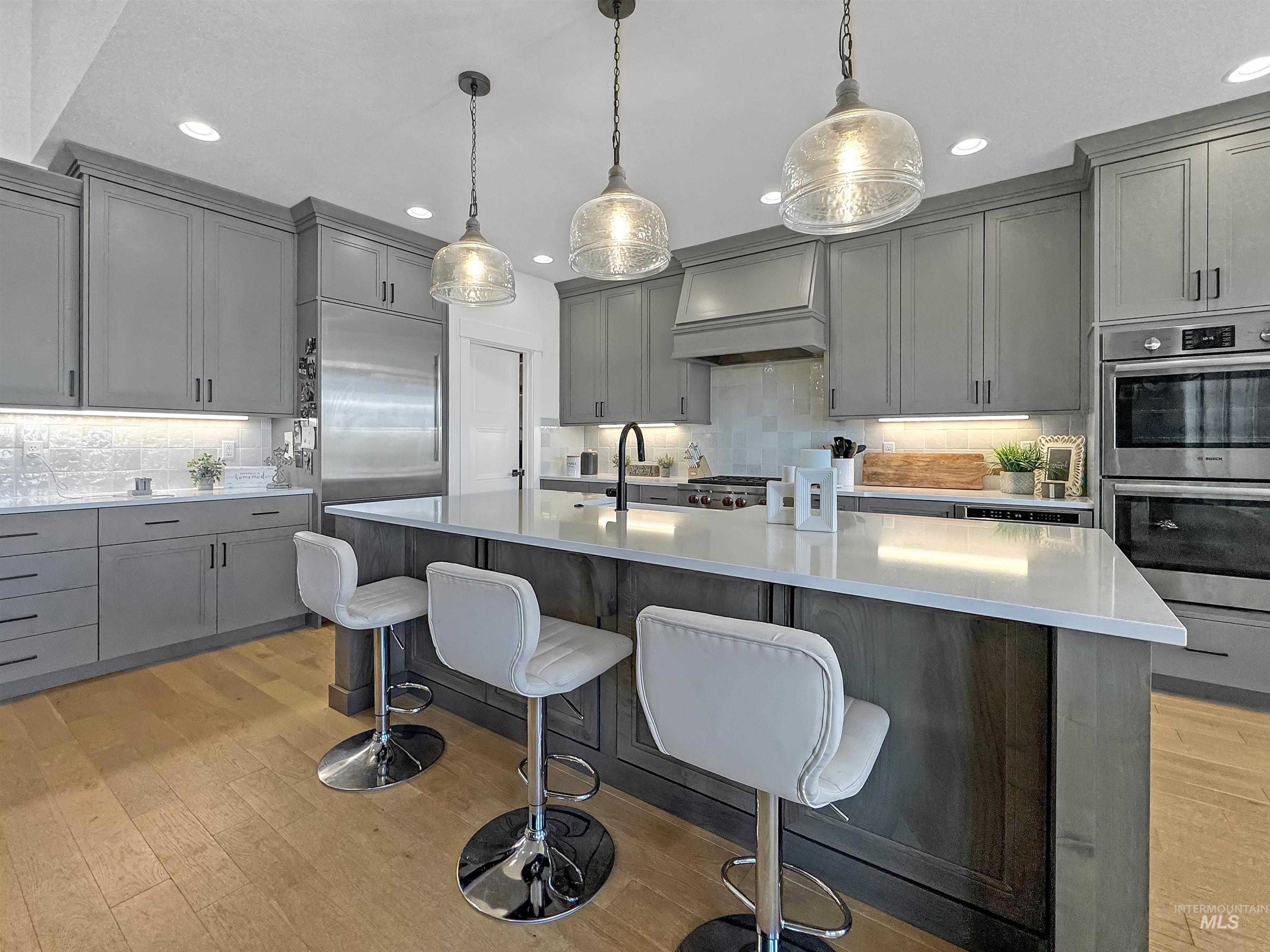 Kitchen featuring gray cabinetry, backsplash, double oven, and recessed lighting