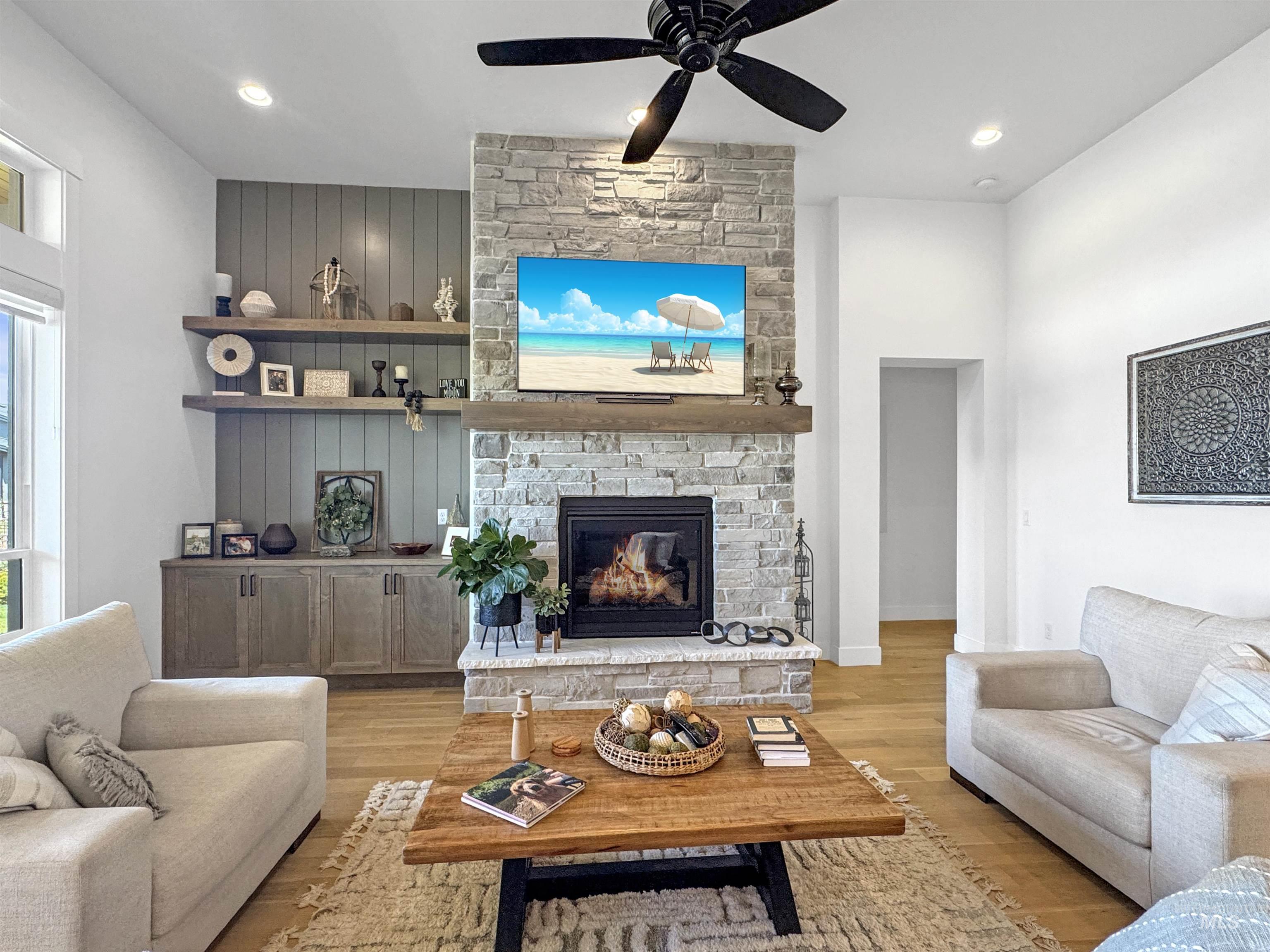 Living room featuring light wood-type flooring, a fireplace, ceiling fan, and recessed lighting