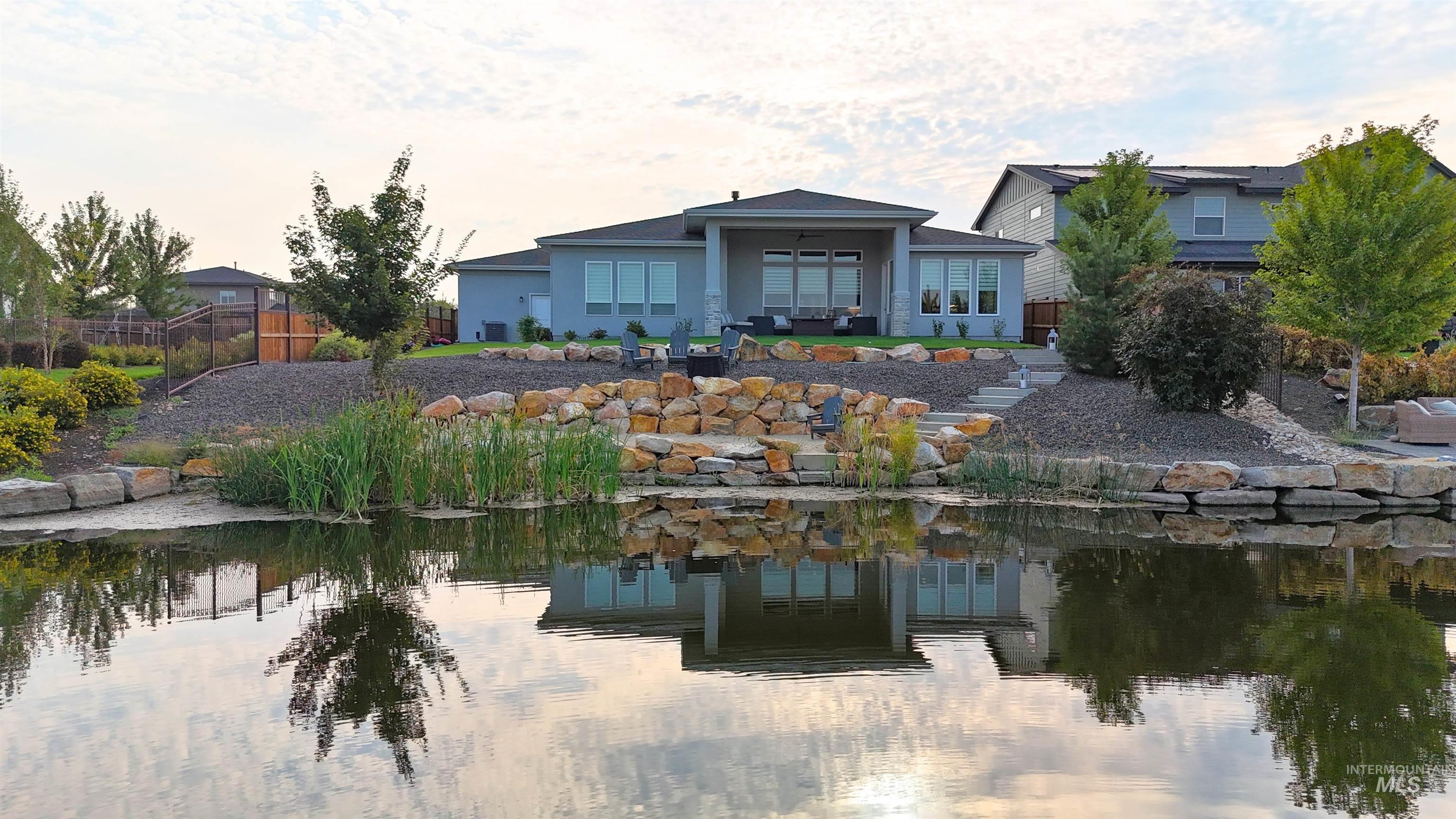 Back of house featuring a patio area, a water view, and stucco siding