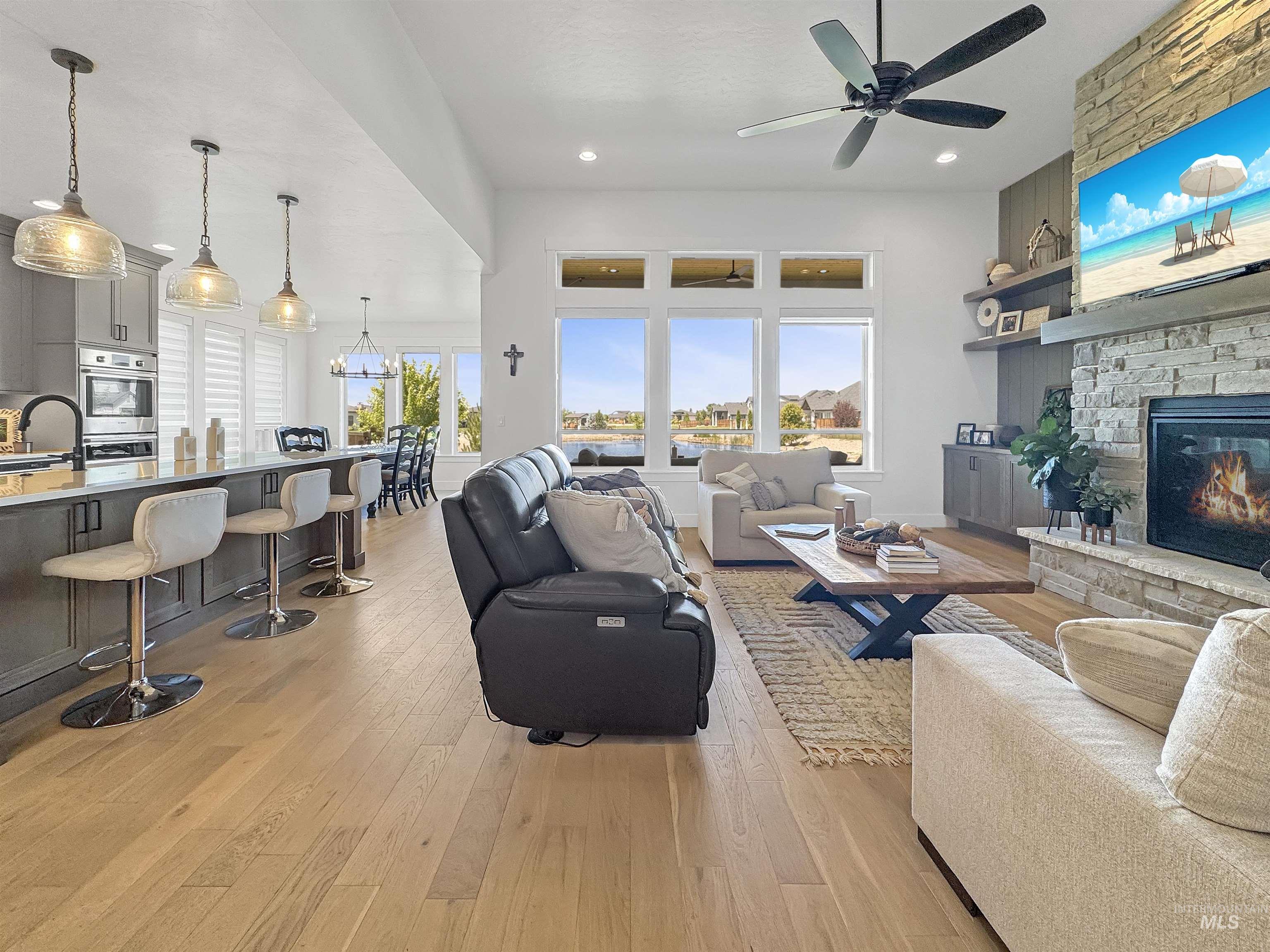 Living area featuring light wood-type flooring, a stone fireplace, recessed lighting, and a ceiling fan