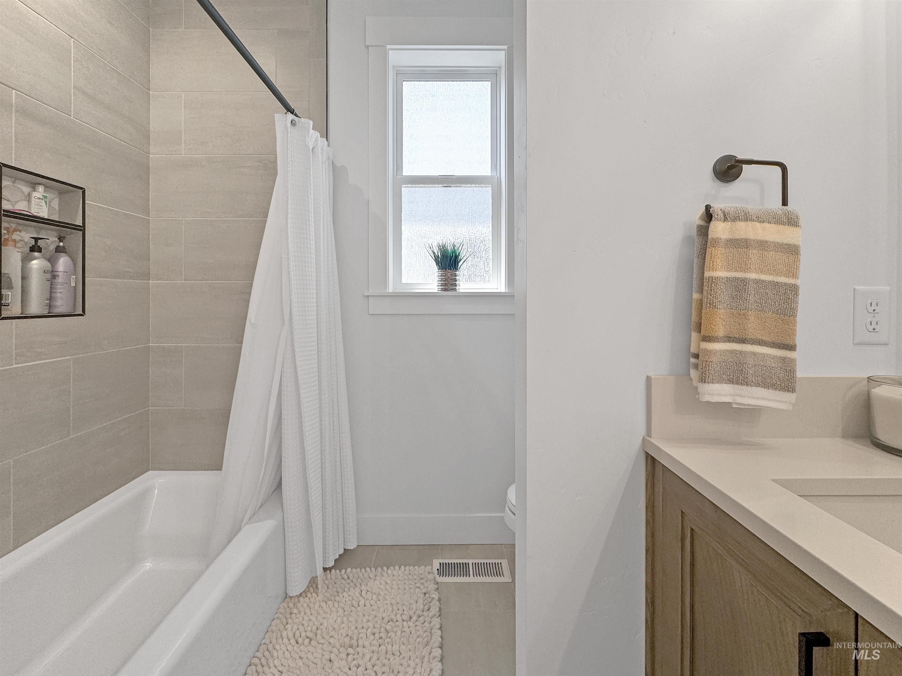 Bathroom featuring shower / tub combo with curtain, vanity, and light tile patterned floors