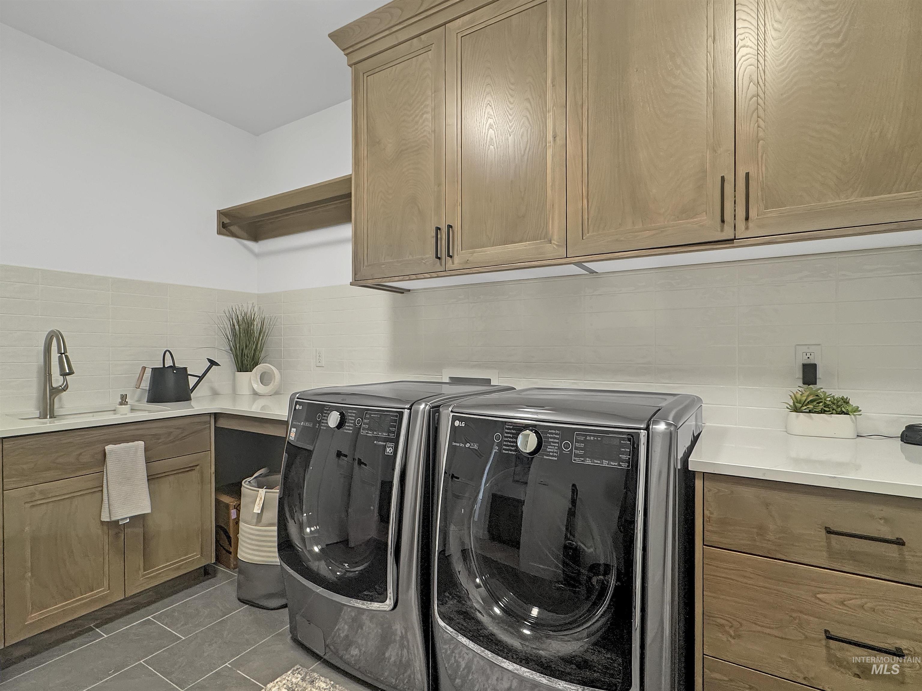 Washroom with cabinet space, tile patterned floors, and washer and clothes dryer