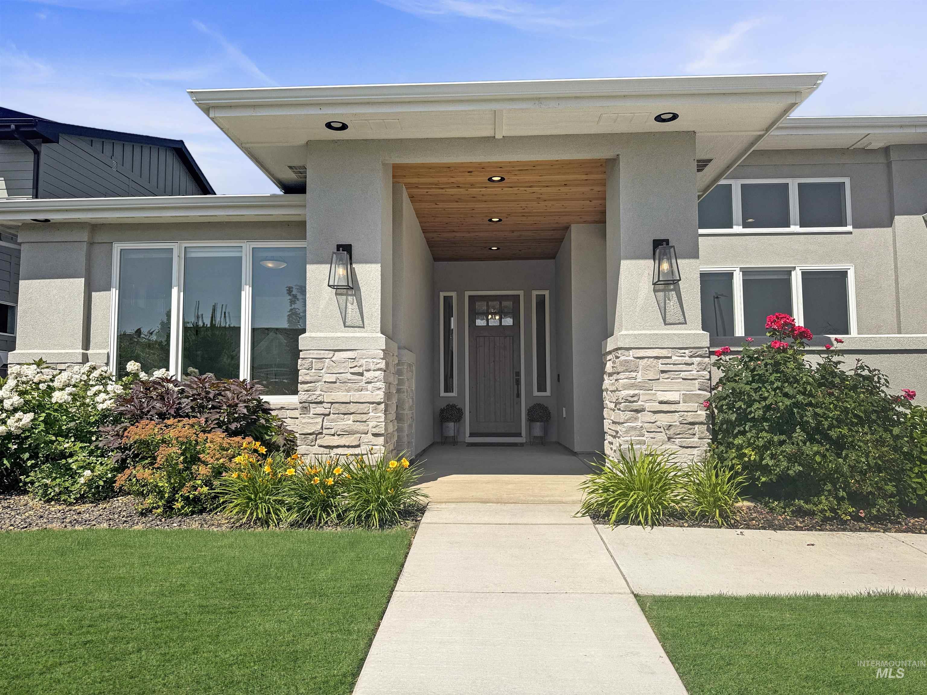 Property entrance featuring stone siding, stucco siding, and covered porch