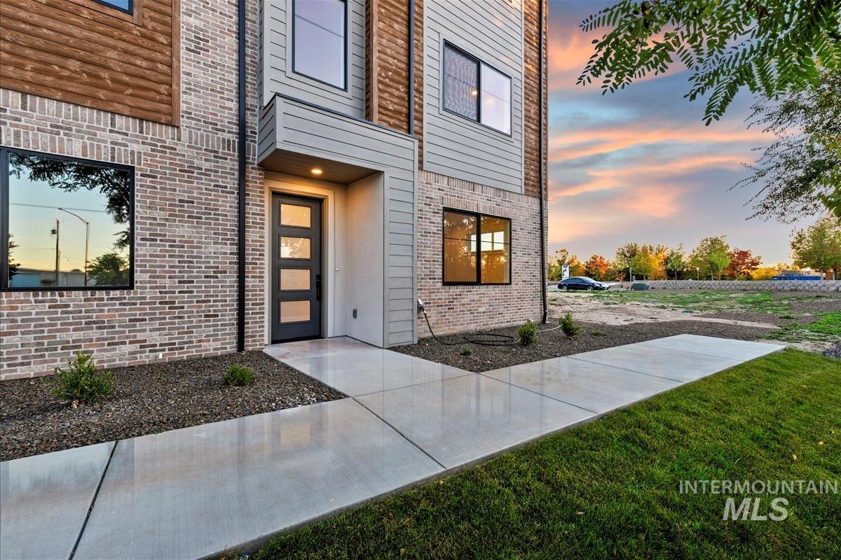 Exterior entry at dusk featuring brick siding and a yard