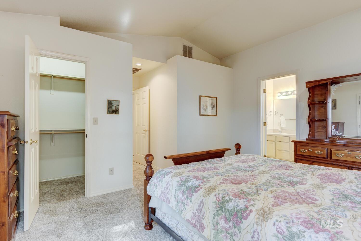 Bedroom with light carpet, a walk in closet, and lofted ceiling