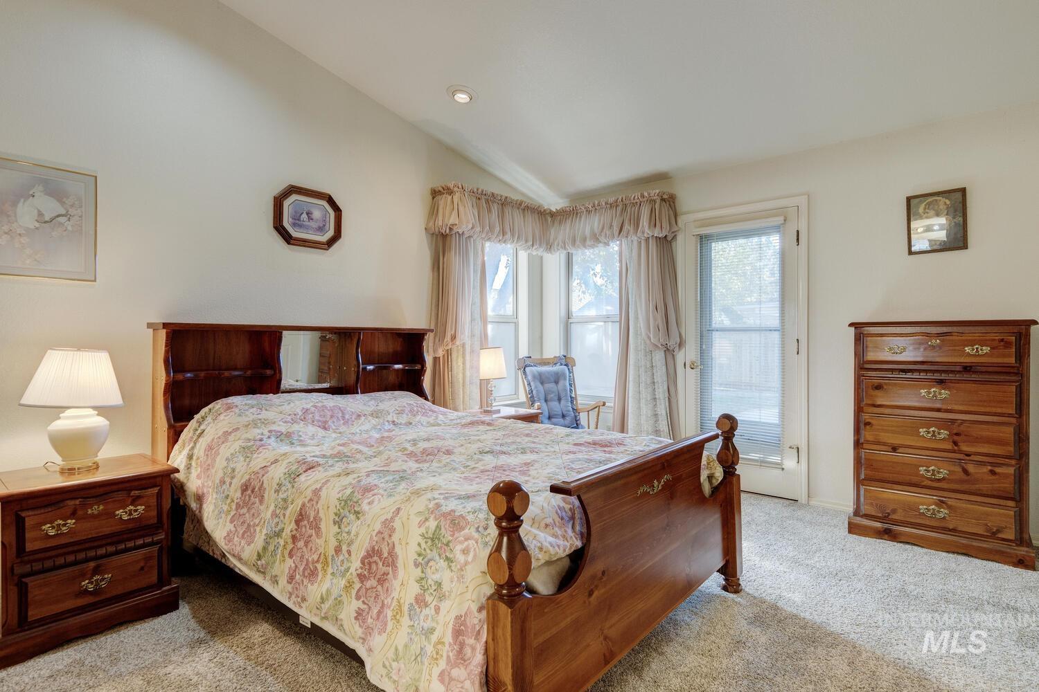 Bedroom featuring vaulted ceiling, light carpet, and access to outside