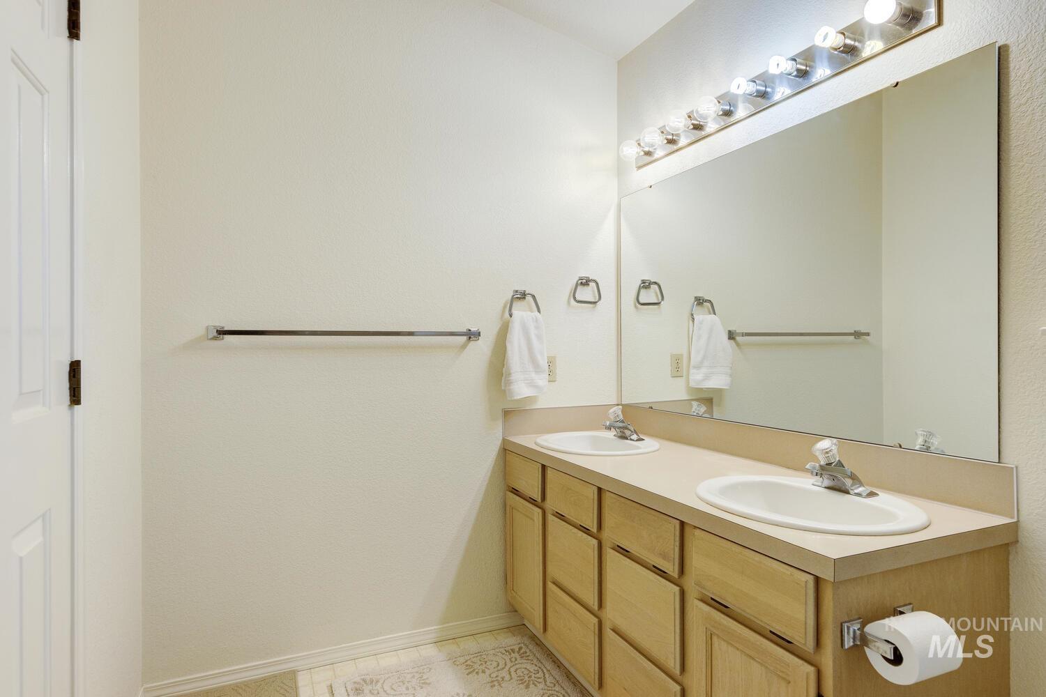 Full bath with double vanity and light tile patterned floors