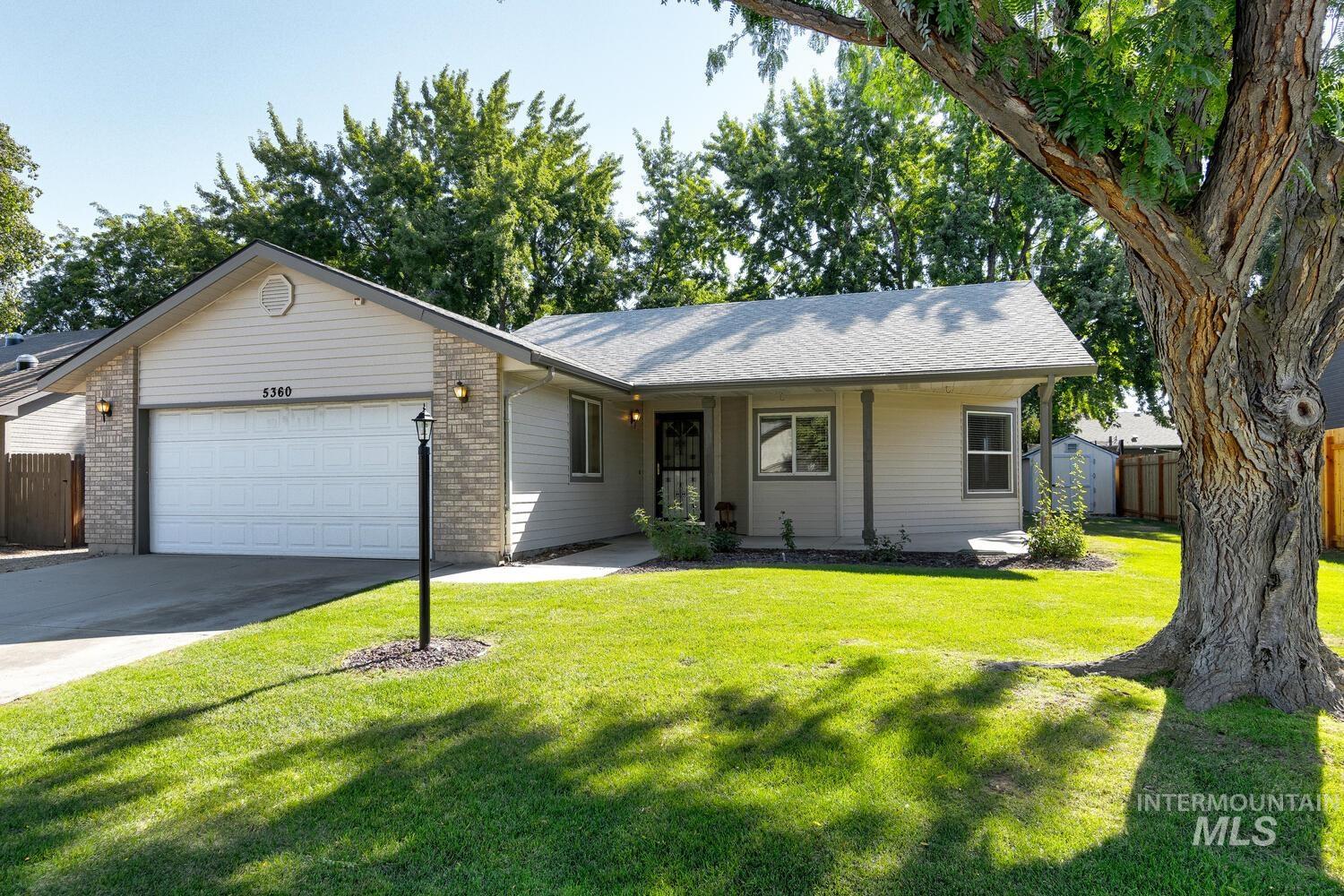 Single story home with driveway, an attached garage, brick siding, and a shingled roof