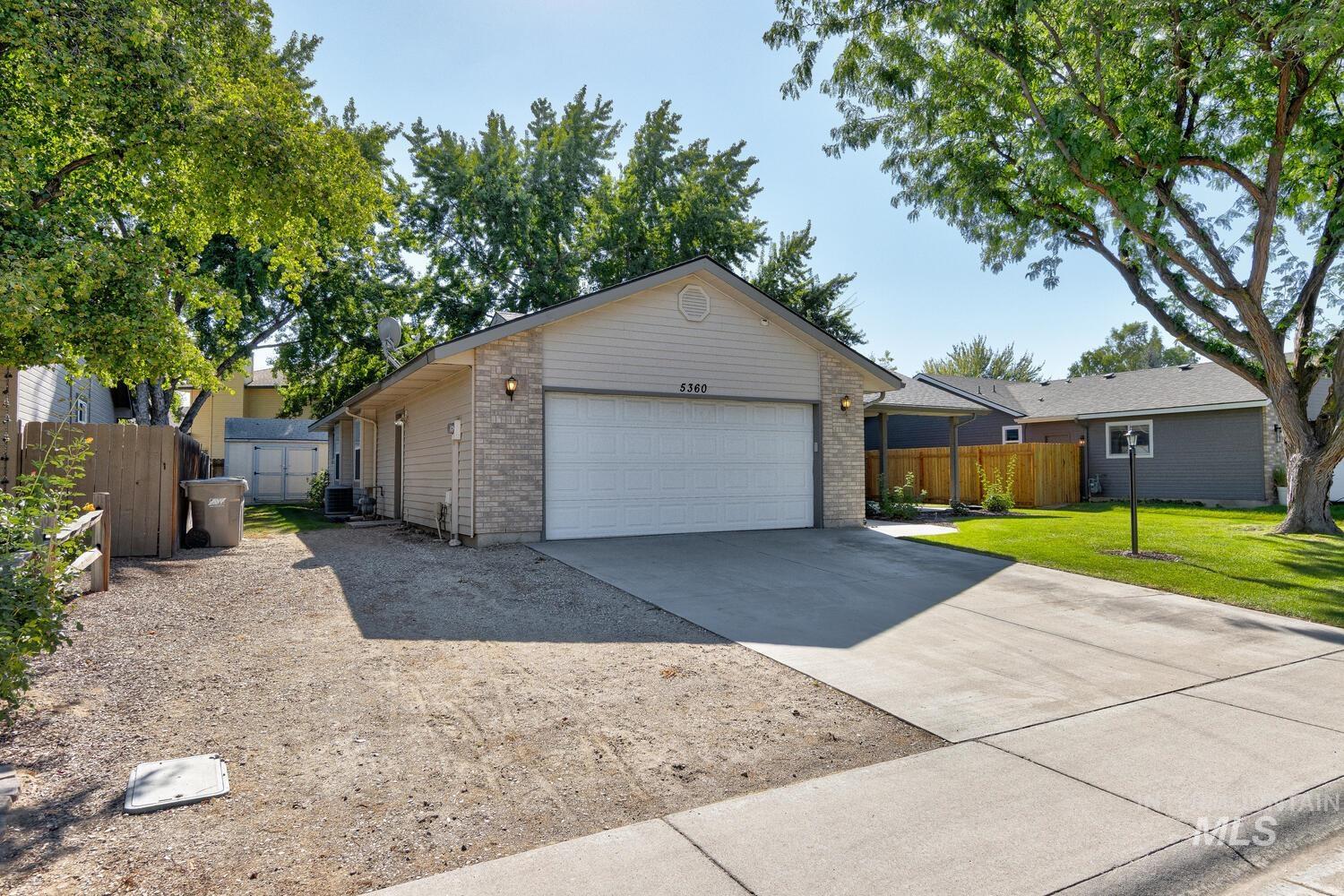 Ranch-style house with an outbuilding, concrete driveway, brick siding, and a garage
