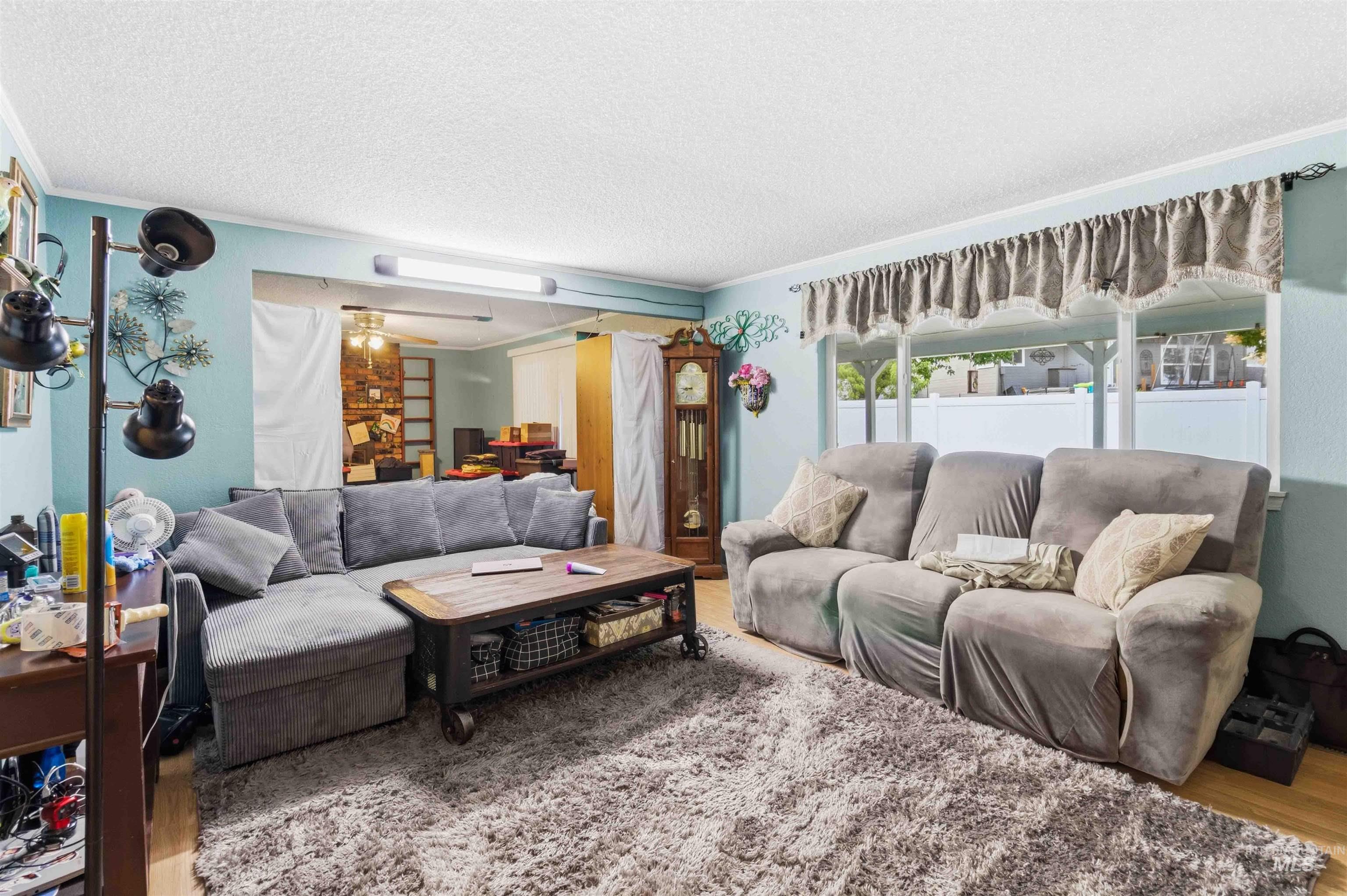 Expansive living area featuring light-toned flooring, a textured area rug, and light blue wall tones