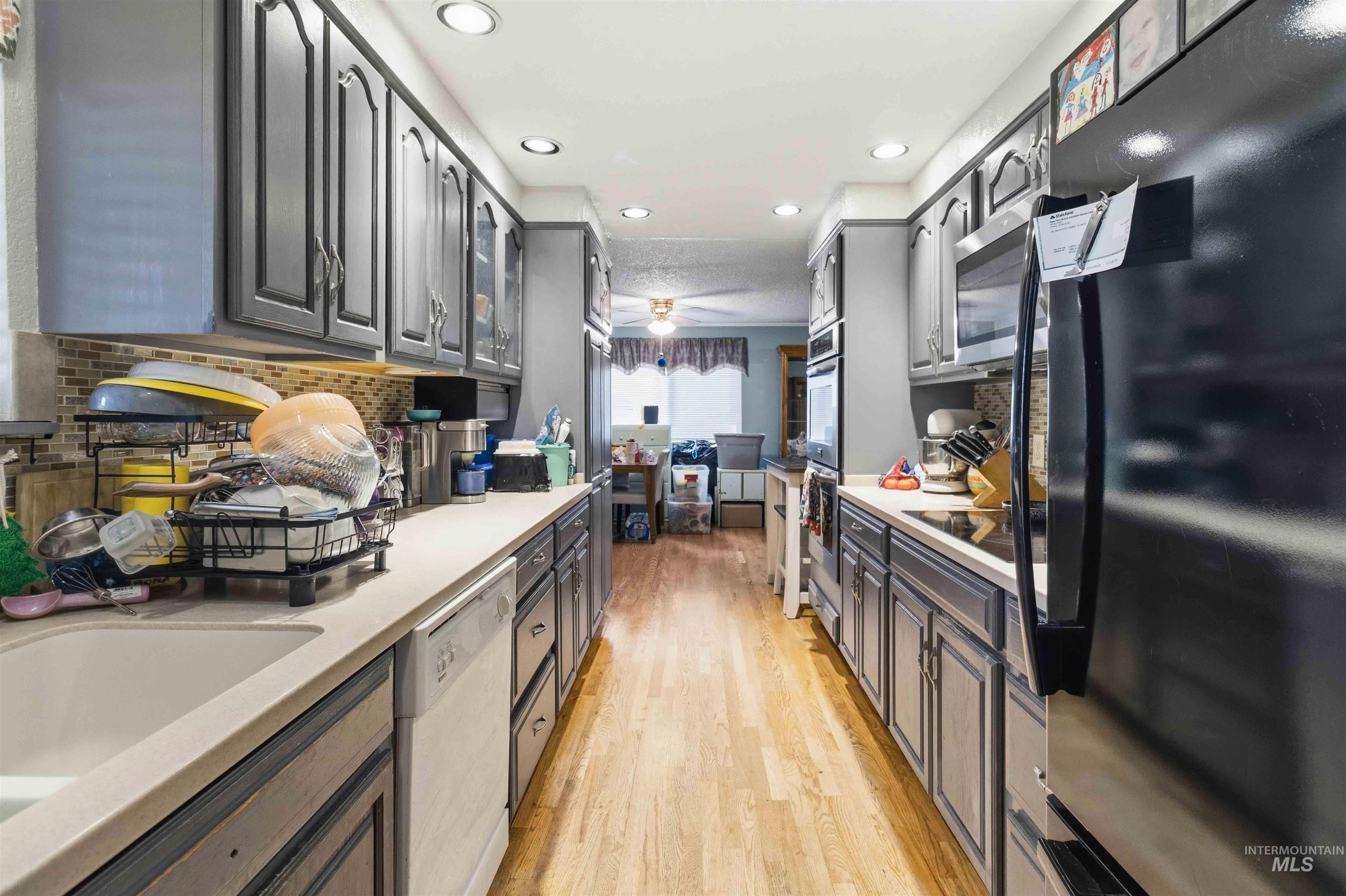 Galley kitchen featuring wood-finish flooring, recessed lighting, and gray cabinetry