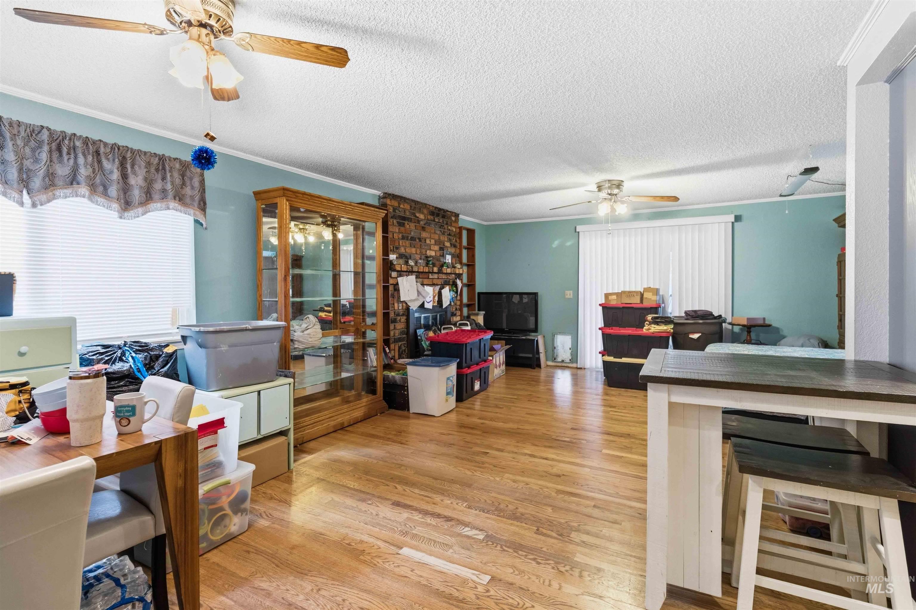 Expansive room featuring wood-finish flooring, light blue walls, and multiple ceiling fans