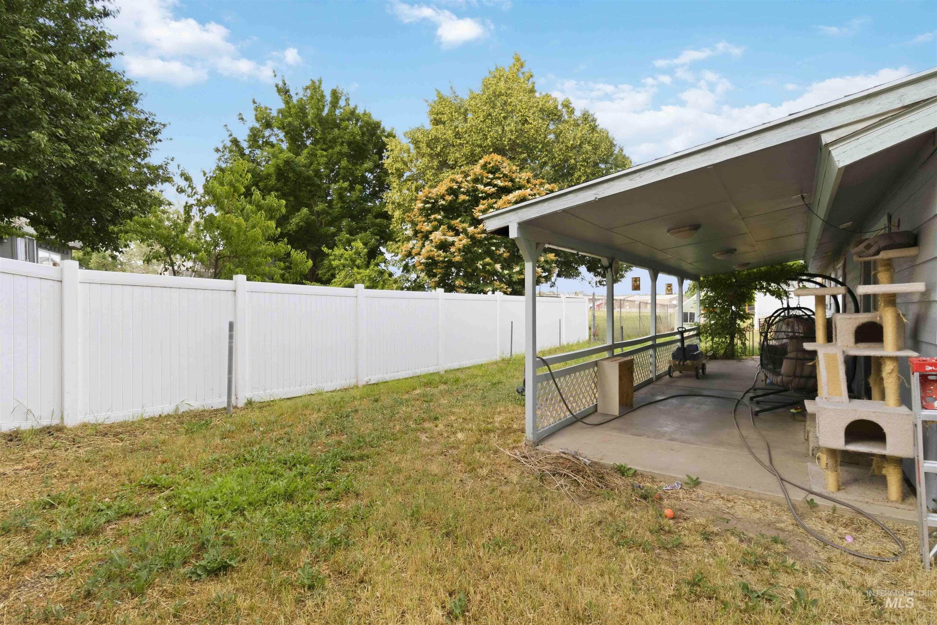 Covered patio with concrete flooring, supported by white columns, extending from the residence
