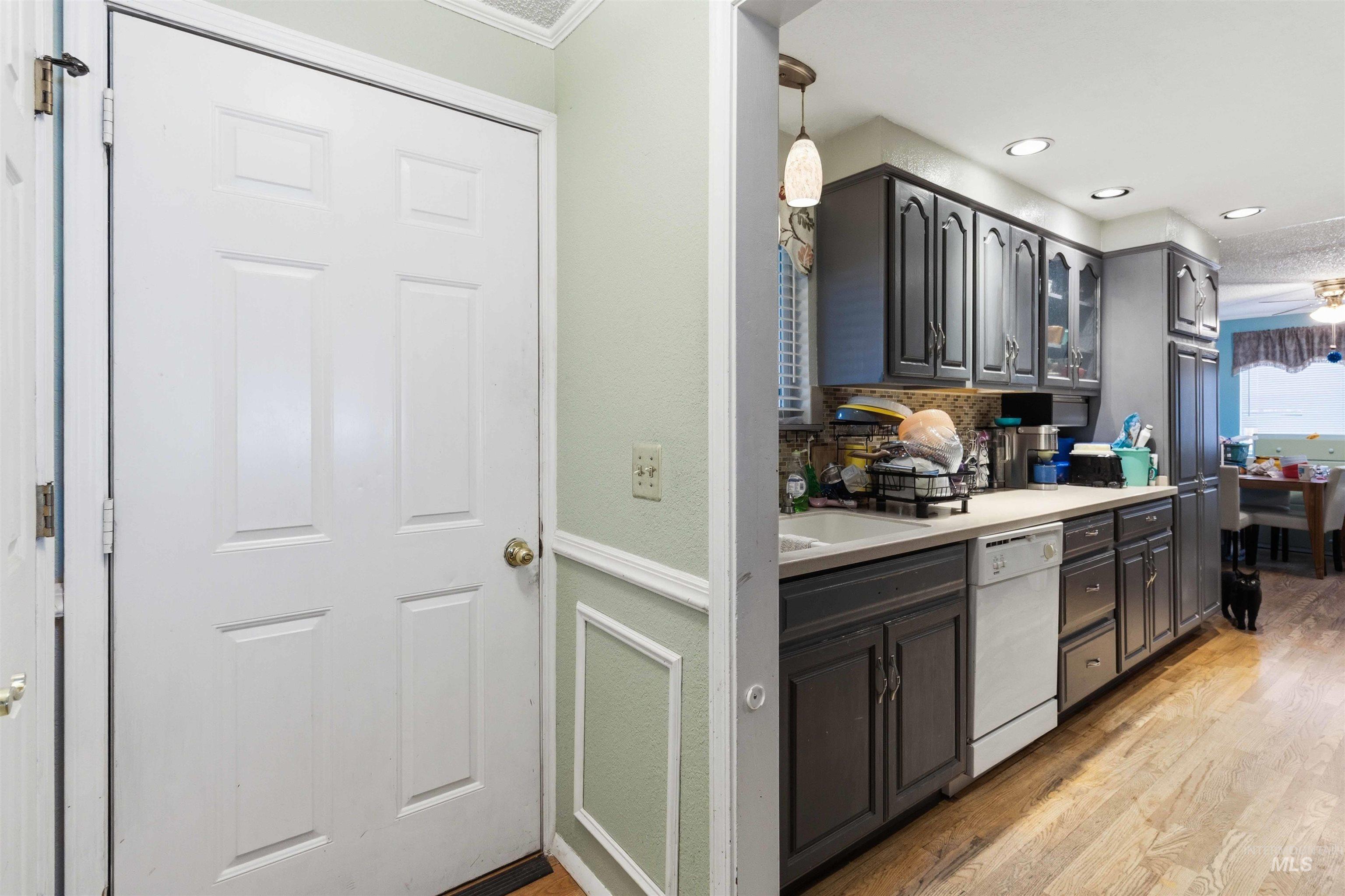 Kitchen featuring dark cabinetry, recessed lighting, wood-finish flooring, a pendant light fixture, and a built-in dishwasher
