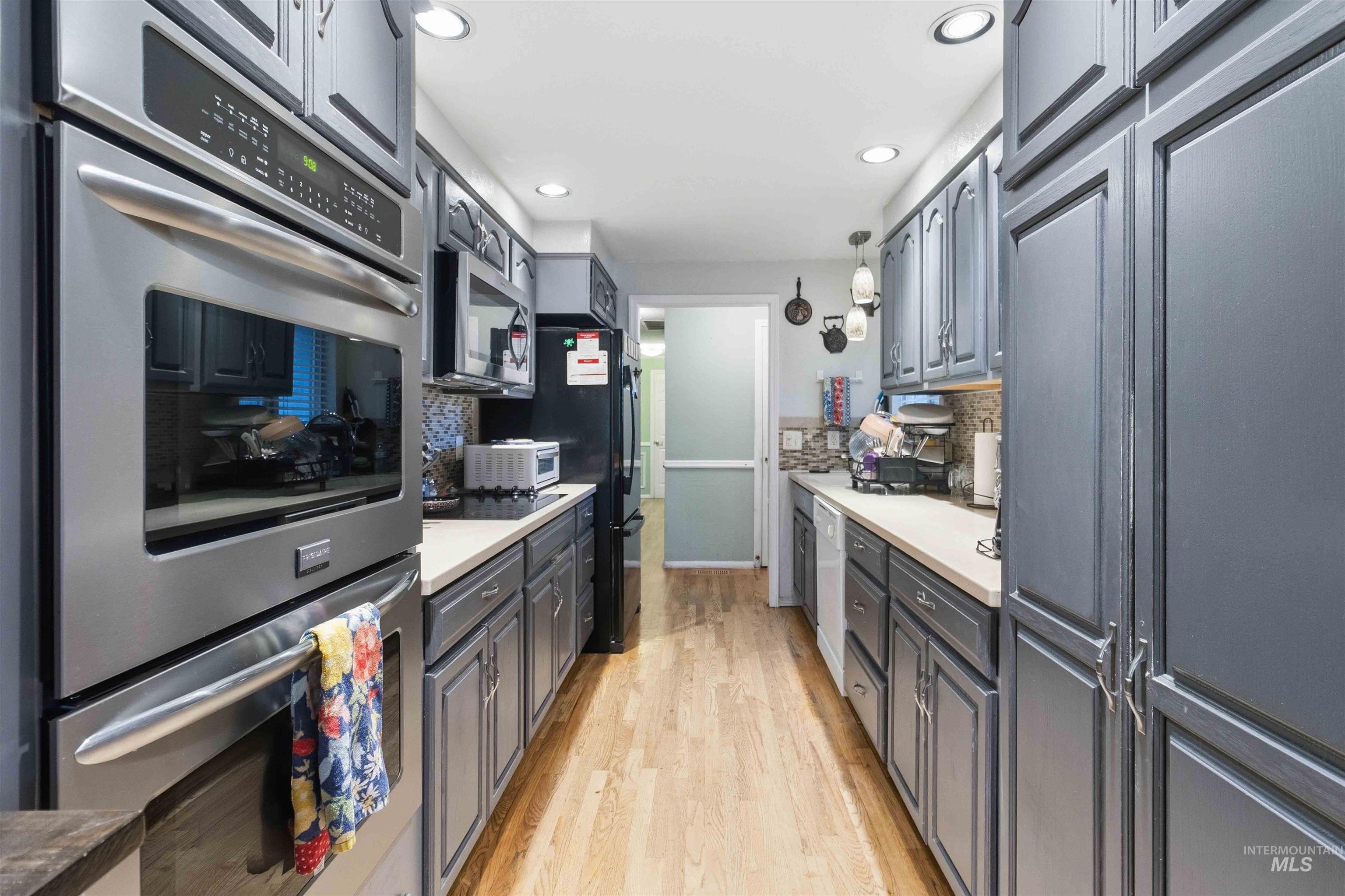 Galley kitchen featuring wood-finish flooring, recessed lighting, and grey paneled cabinetry