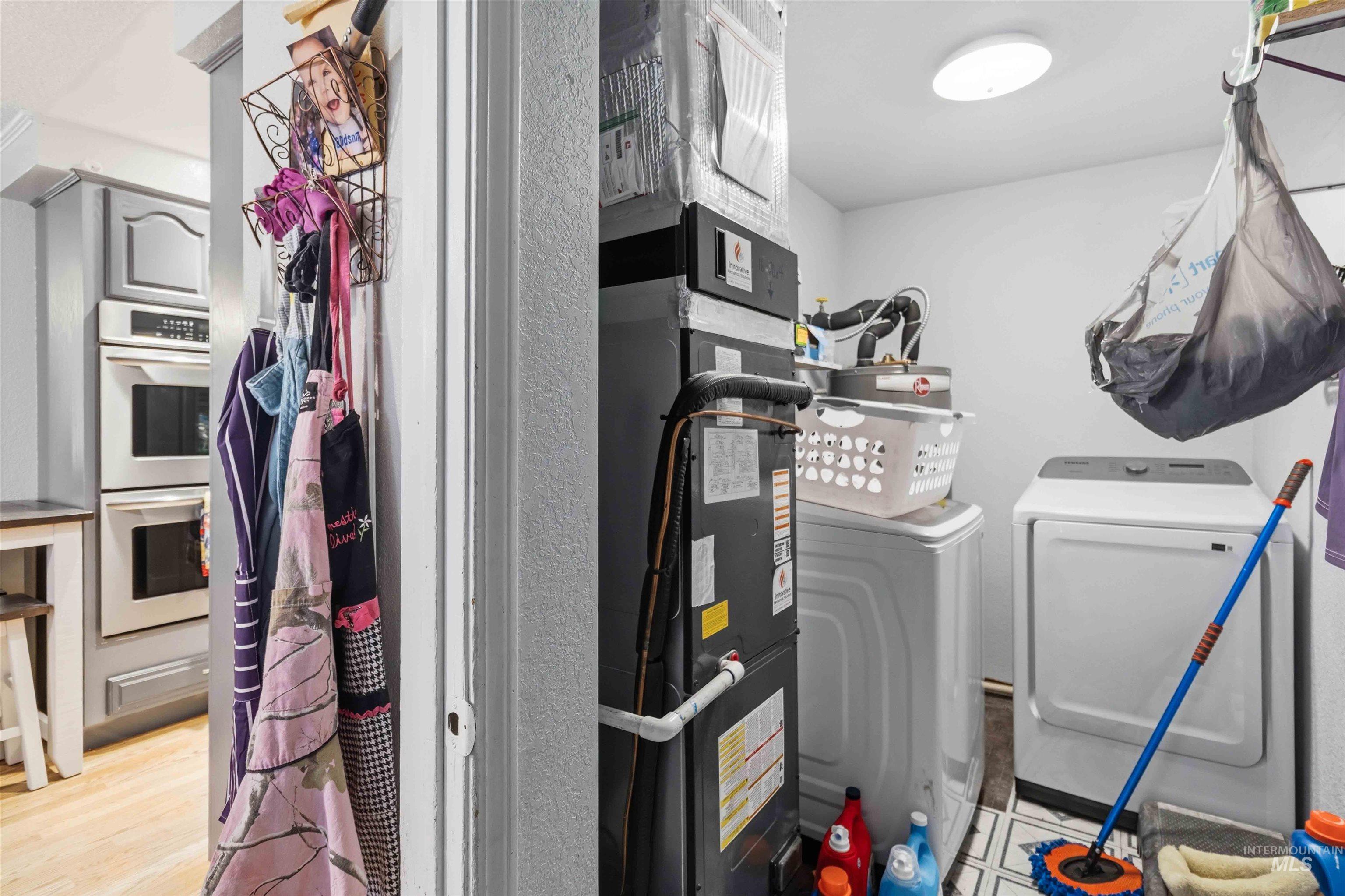 Dedicated utility space featuring a modern washer and dryer set, white walls, and geometric pattern floor tiles