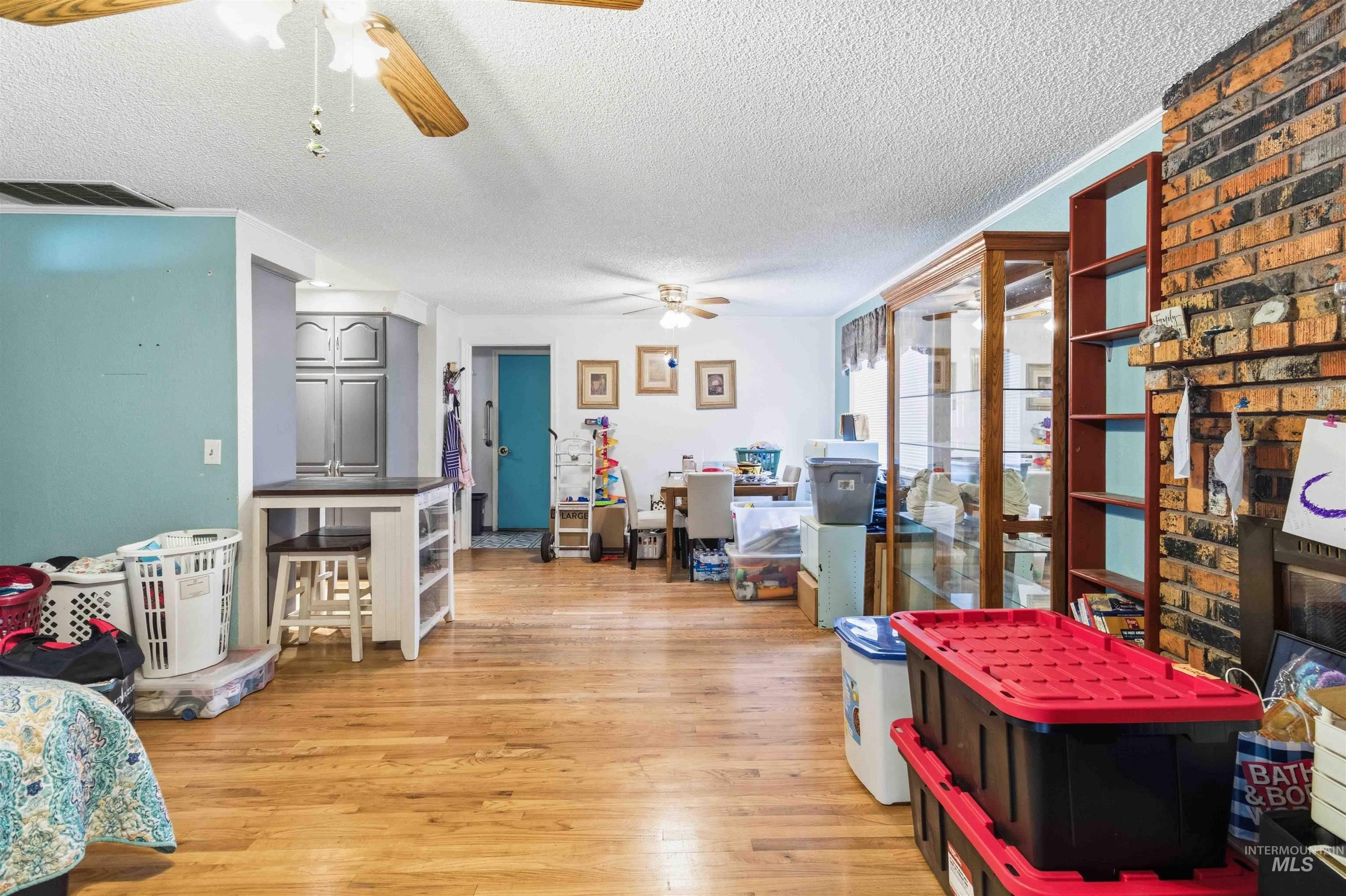 Wood-finish flooring throughout, featuring a brick fireplace surround, light blue accent walls, and ceiling fans