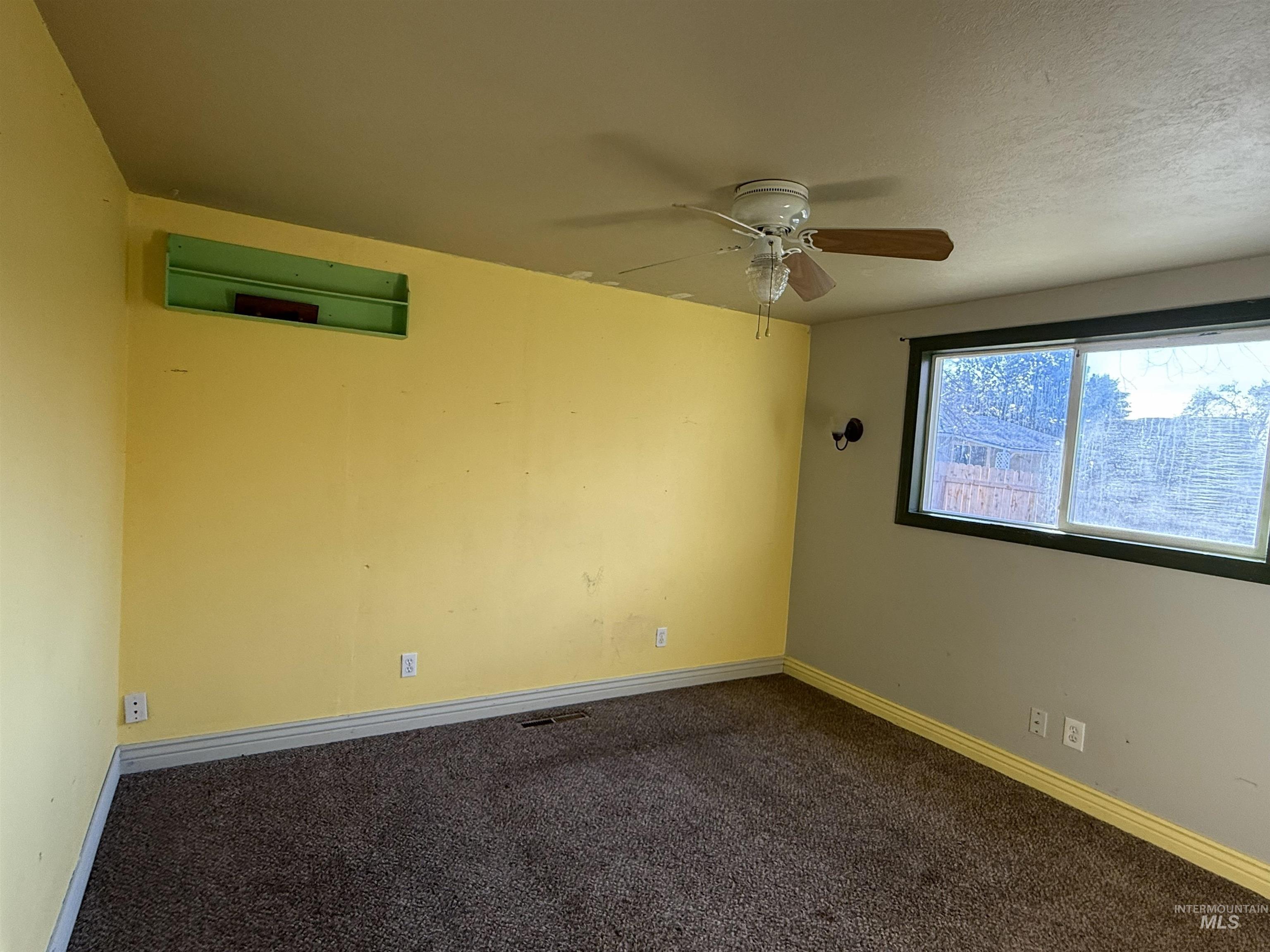 Carpeted spare room featuring ceiling fan, a wall mounted air conditioner, and a textured ceiling