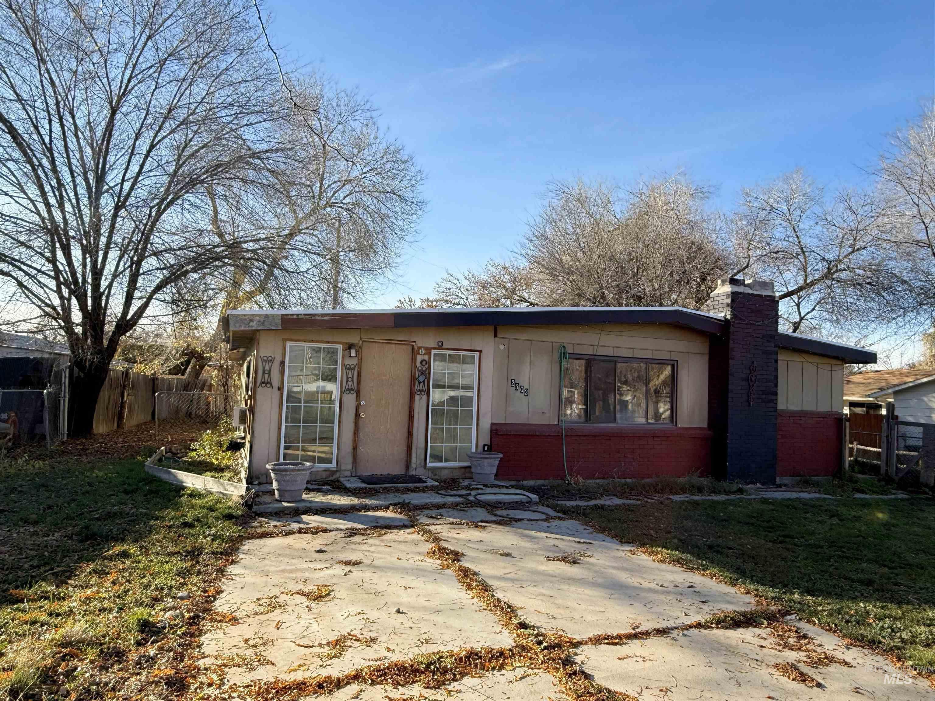 View of front of home featuring a chimney, brick siding, and board and batten siding