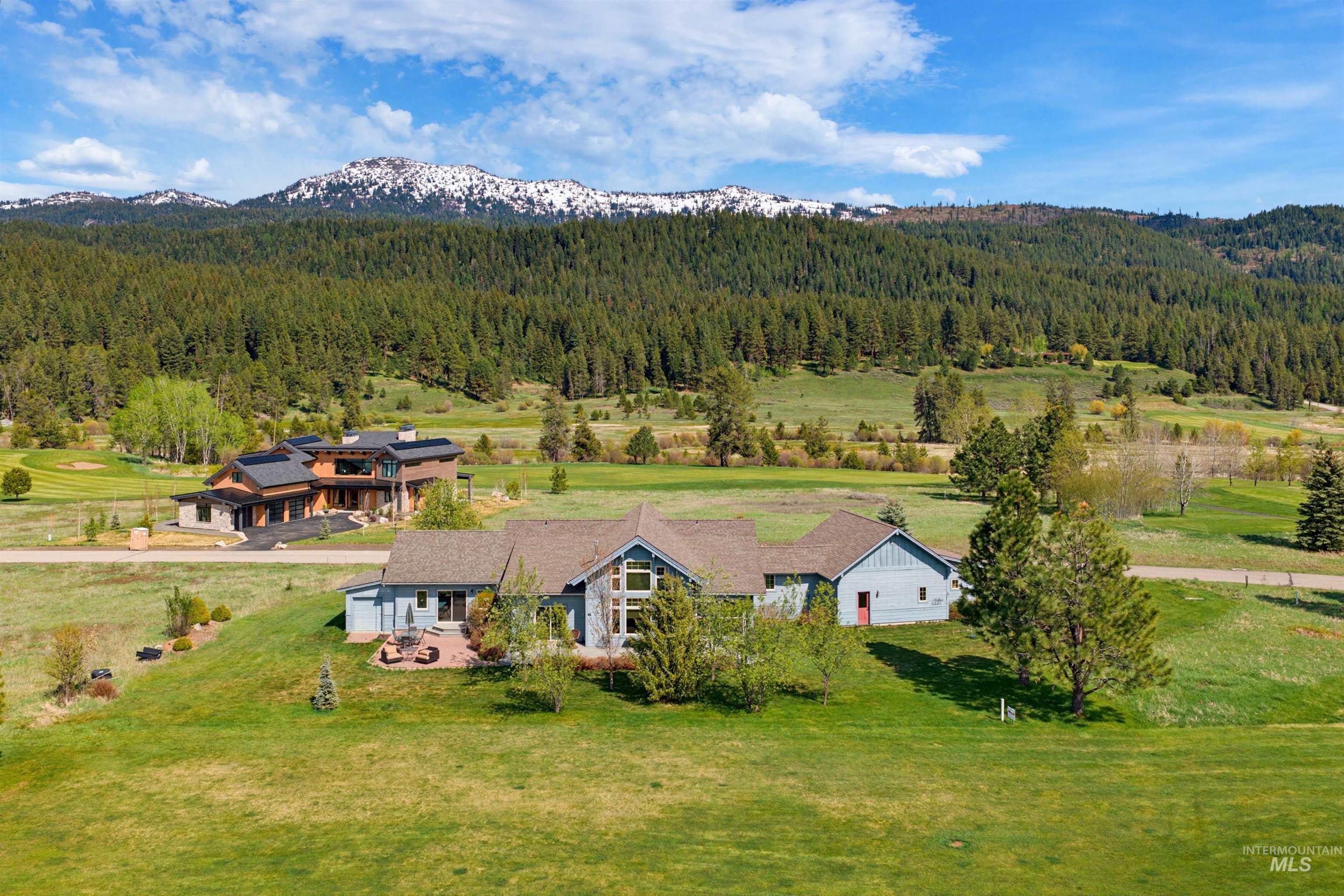 Spacious property set against a backdrop of a forested mountain with snow-capped peaks