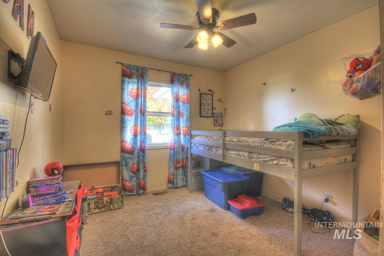 Carpeted bedroom with ceiling fan and baseboards