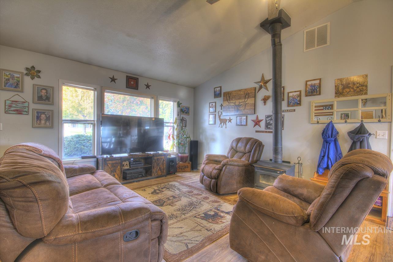 Living room featuring a wood stove, vaulted ceiling, and wood finished floors