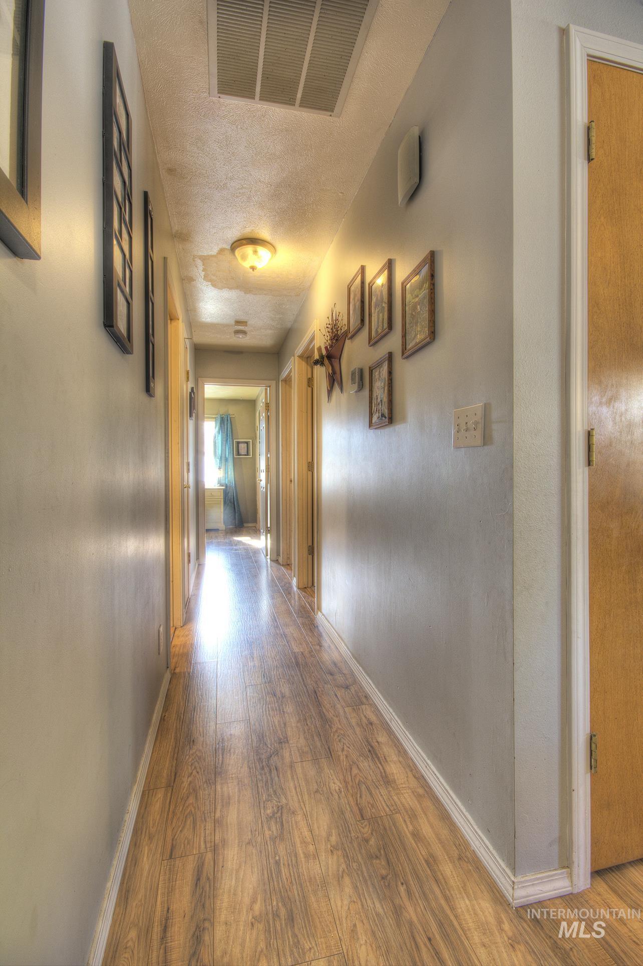Hallway with wood finished floors and a textured ceiling