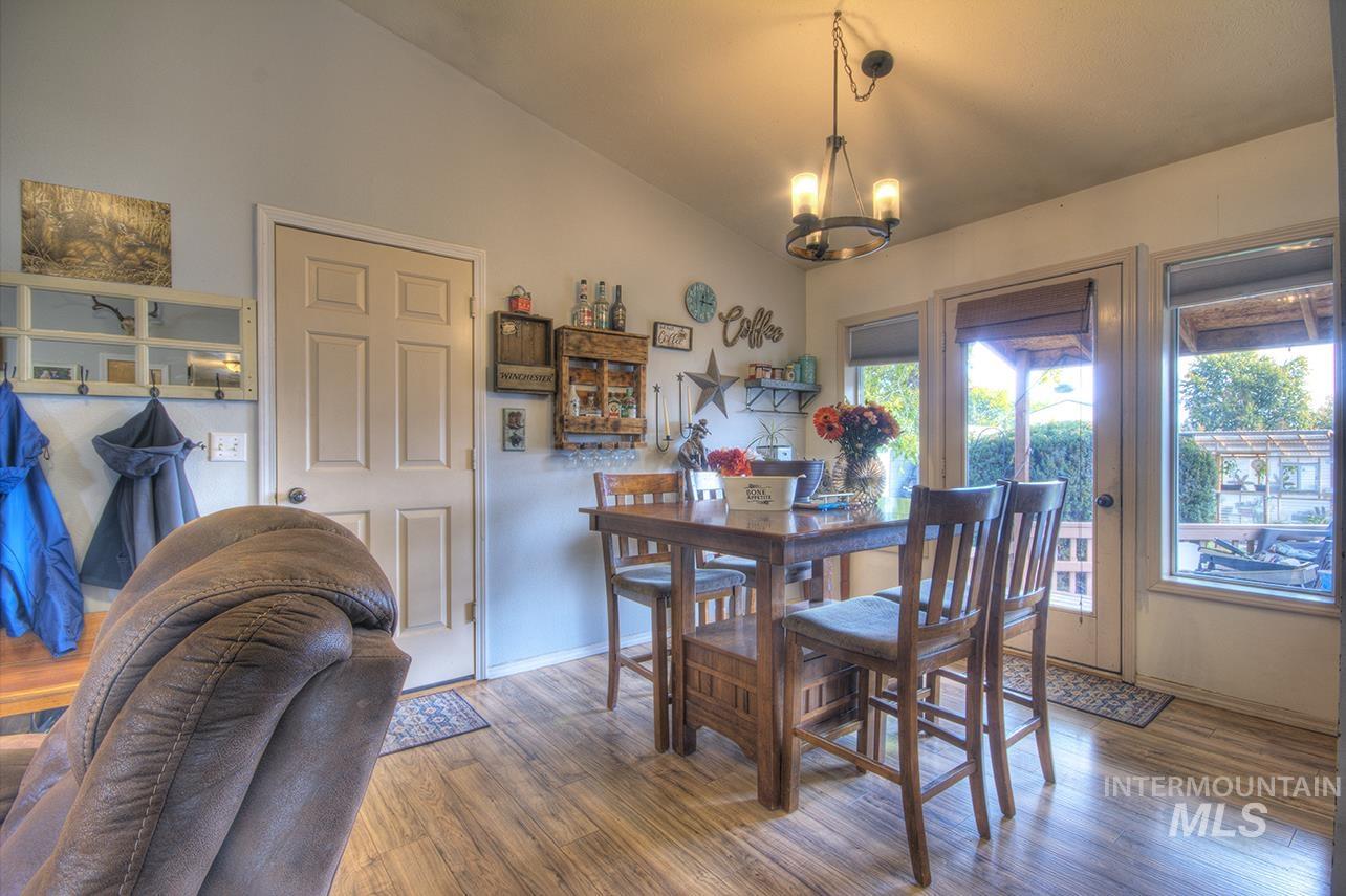 Dining room with lofted ceiling, wood finished floors, and a chandelier