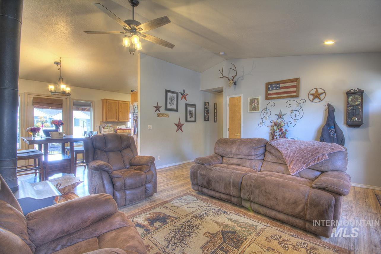 Living area with vaulted ceiling, wood finished floors, ceiling fan, and a chandelier