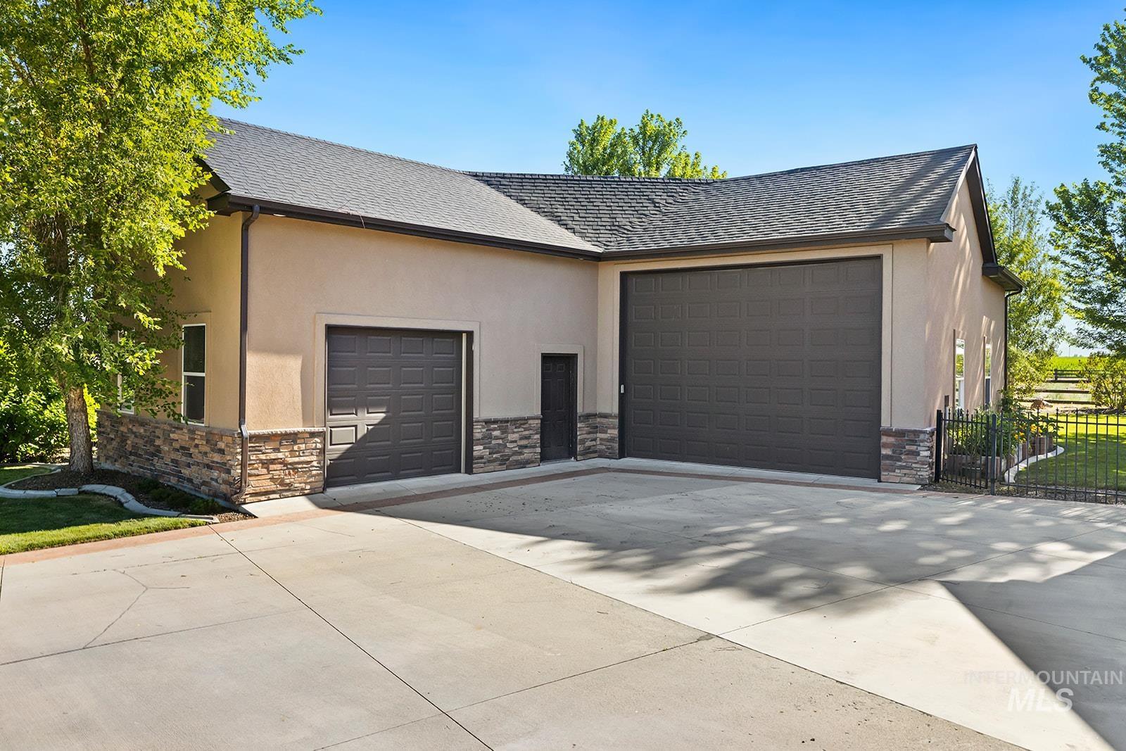 View of side of property featuring stone siding, concrete driveway, and roof with shingles