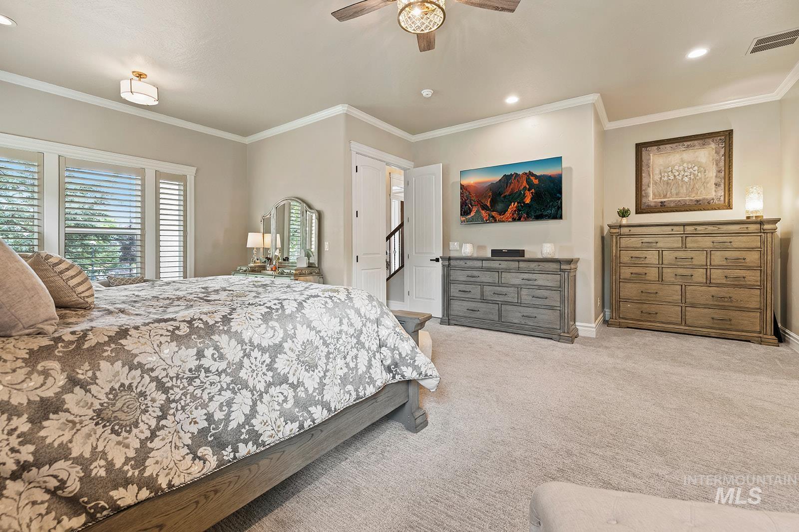 Carpeted bedroom featuring ornamental molding, recessed lighting, and a ceiling fan