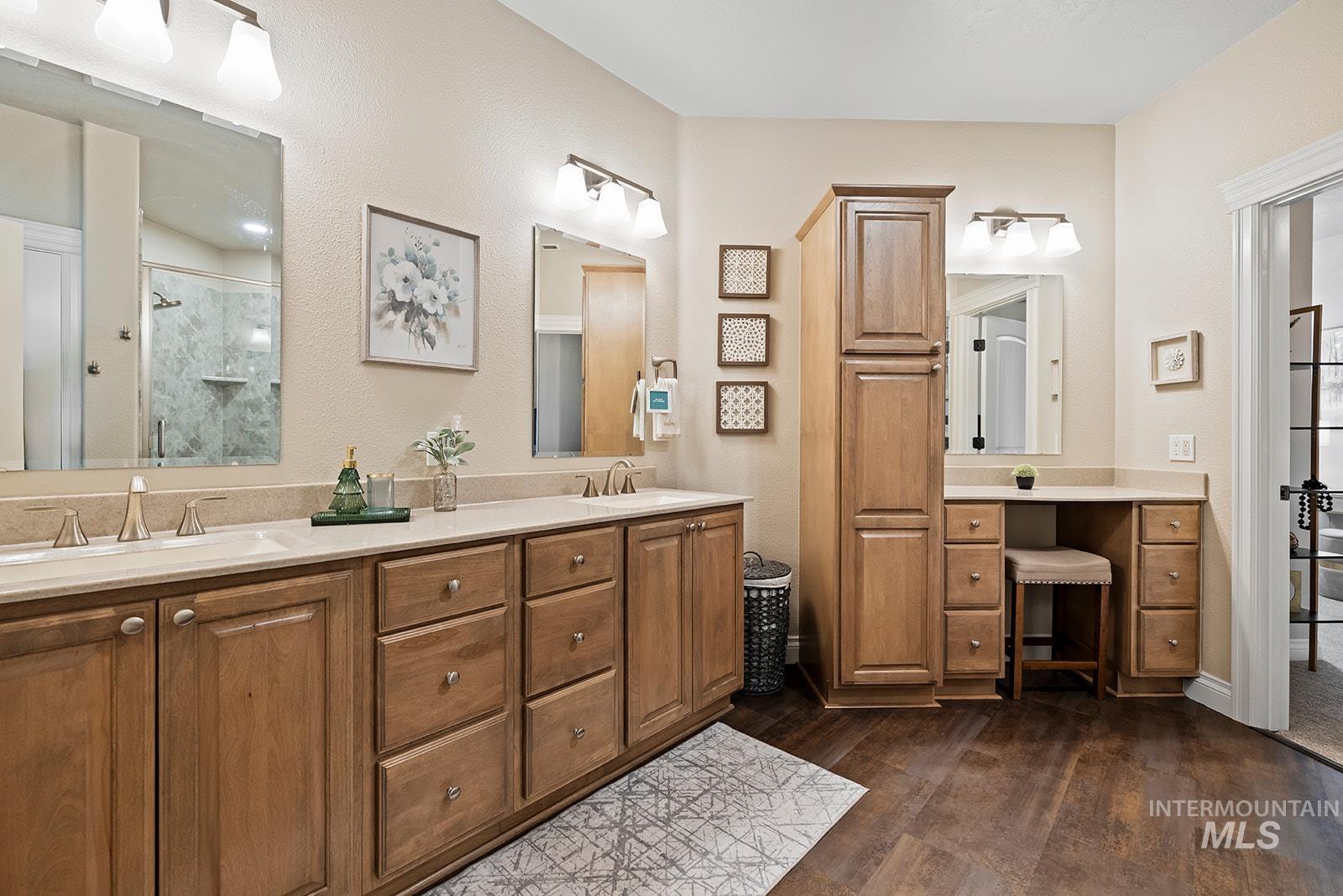 Bathroom with a stall shower, double vanity, and dark wood-style floors
