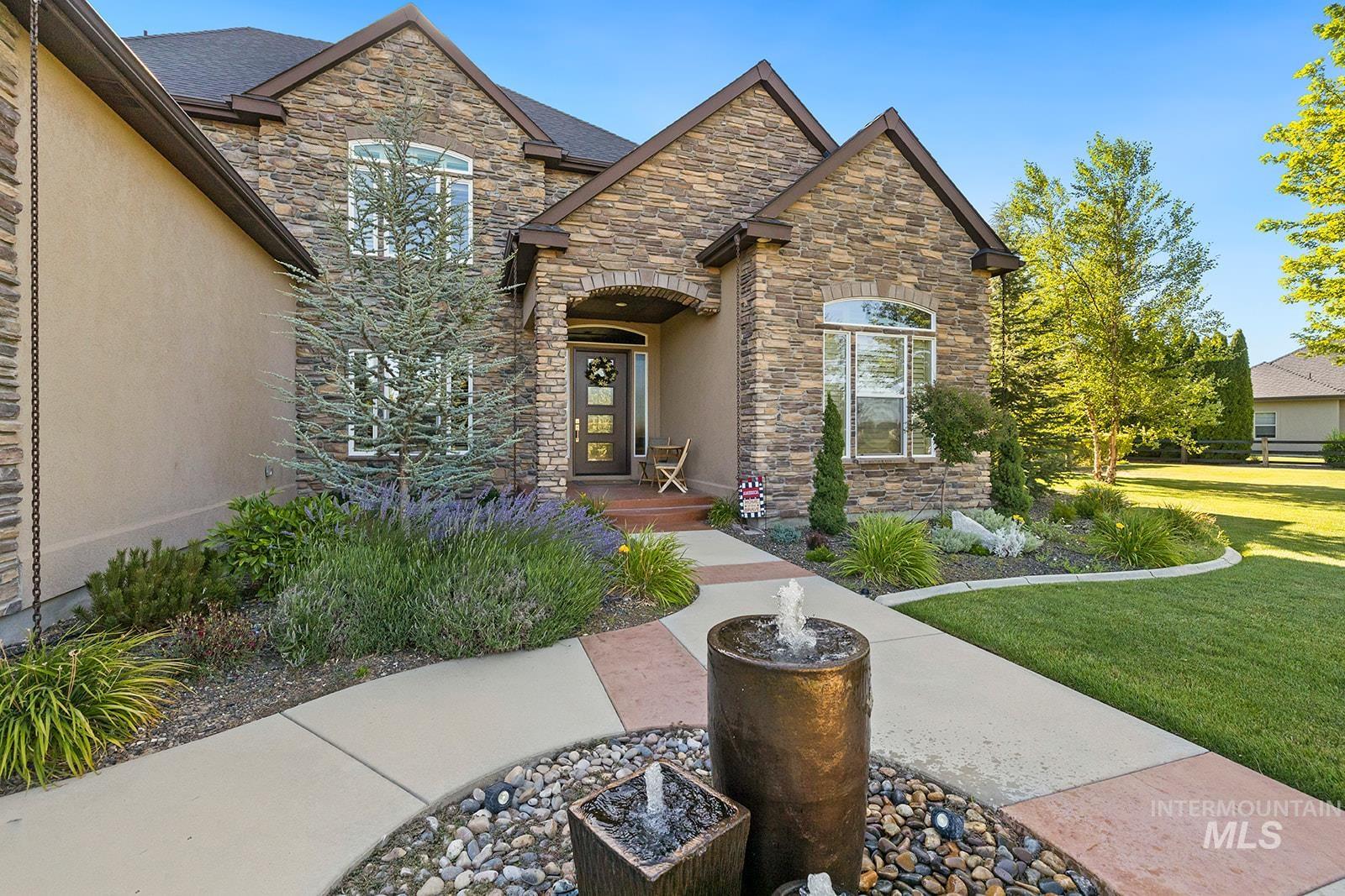 View of front of house with a front yard, stone siding, and stucco siding