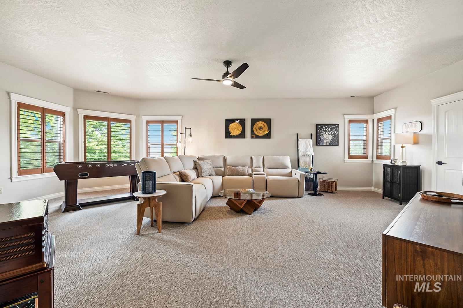 Carpeted living room with a textured ceiling and ceiling fan